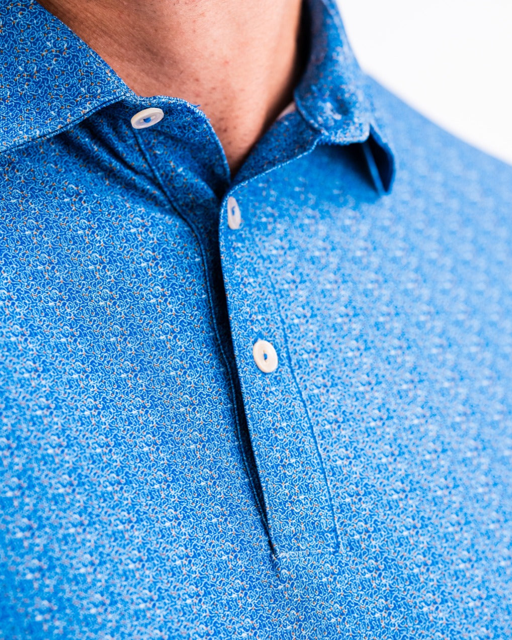 Close-up of the Player Preferred Polo in Cosmic Swirl, featuring a vibrant blue pattern and classic collar design.