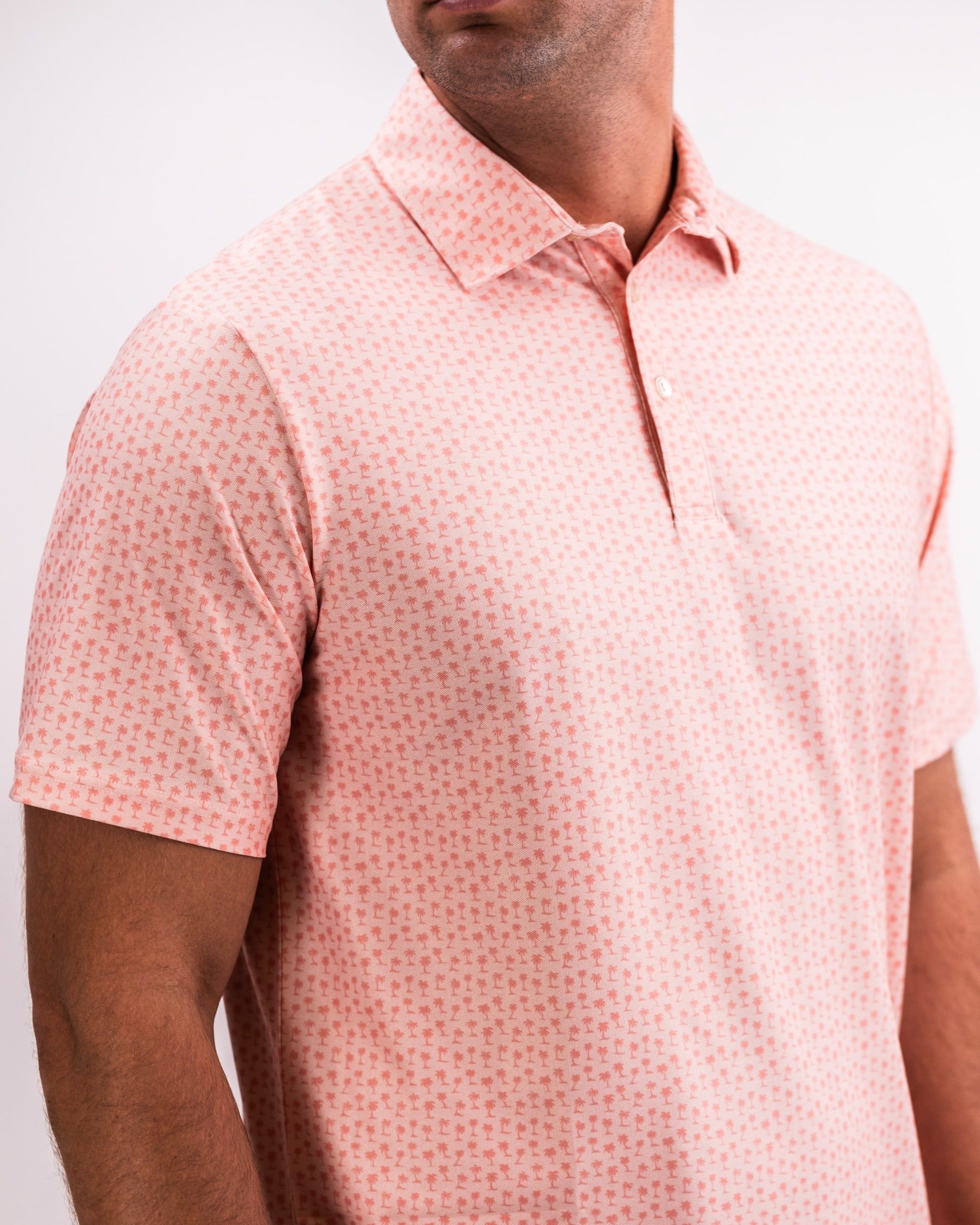 Men's coral polo shirt featuring a palm tree pattern, designed for comfort and style on the golf course.
