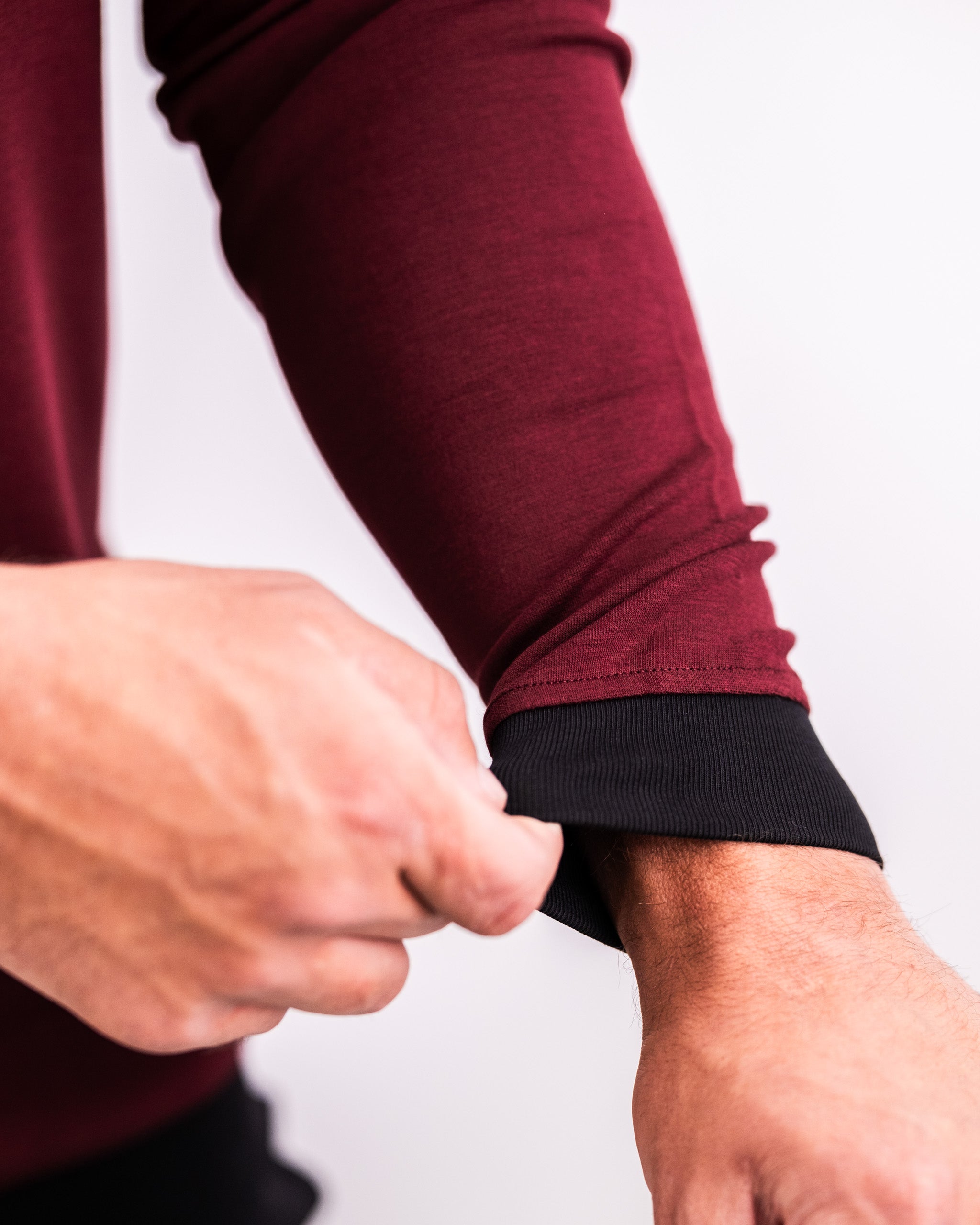 Close-up of a hand adjusting the cuff of a merlot Player Preferred™ crewneck, showcasing its stylish design and fit.