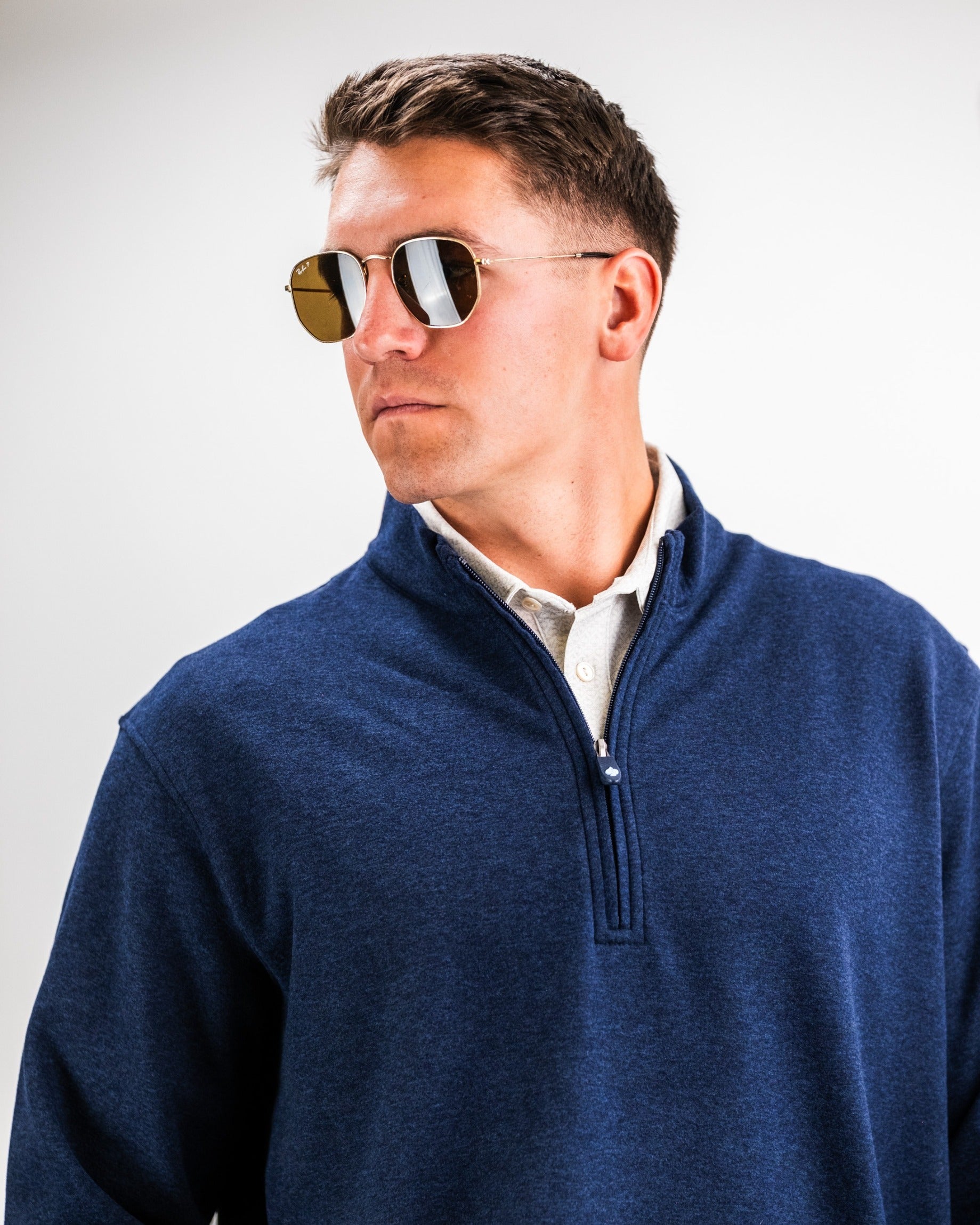 Man wearing a heathered navy pullover with a quarter-zip collar and sunglasses, showcasing a stylish golf look.