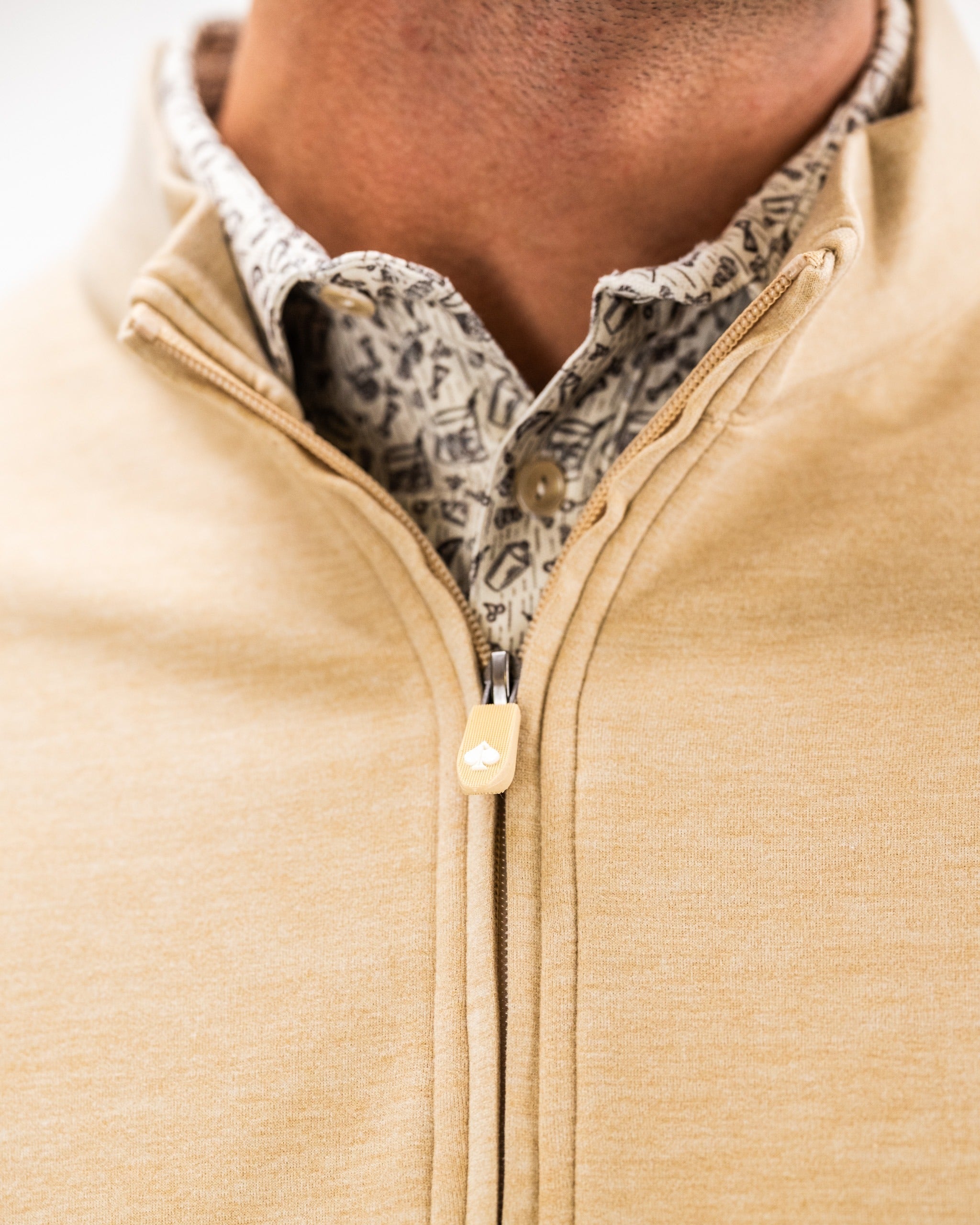 Player Preferred Pullover in sand color features a stylish zip-up design layered over a patterned shirt, perfect for golfers.