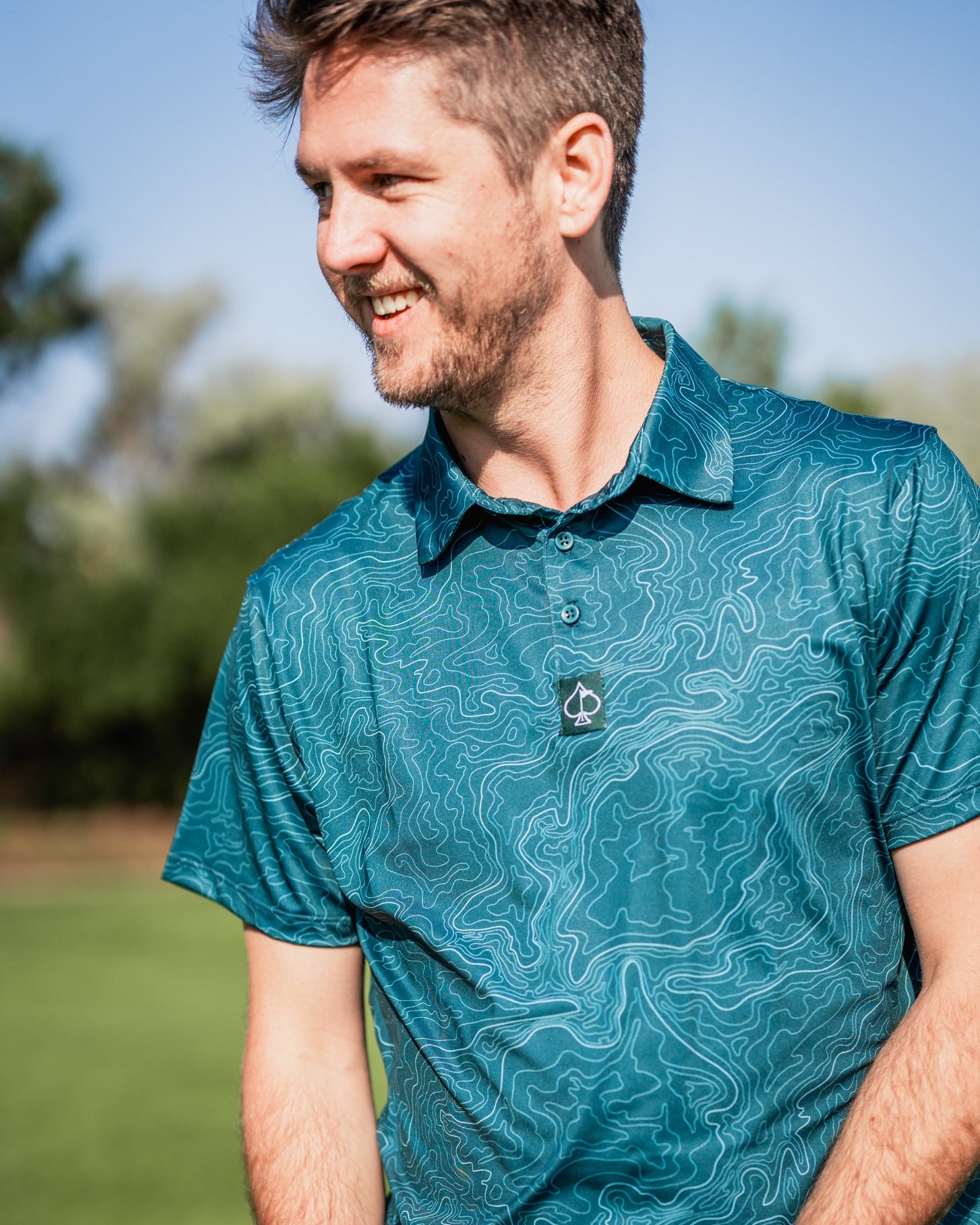 Men's Terrain golf polo featuring a unique topographic pattern in teal, perfect for stylish performance on the course.