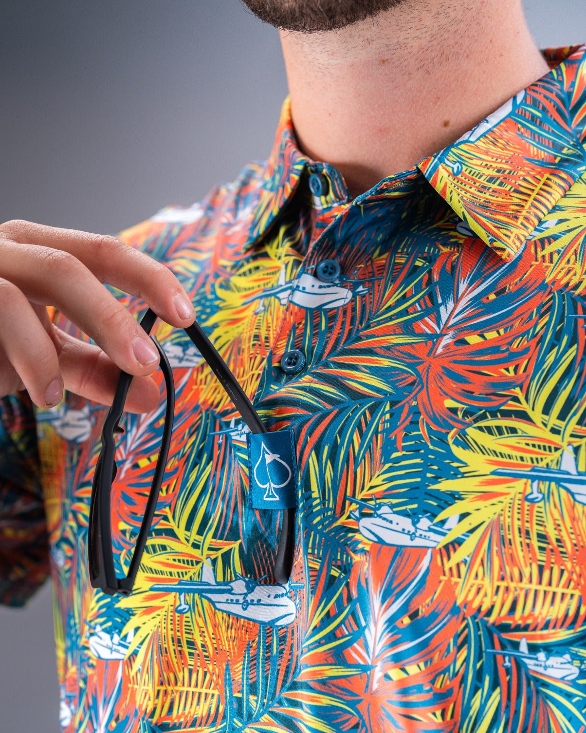 Vibrant Margaritaville Bama Breeze shirt featuring a tropical palm print, with a pocket holding sunglasses.