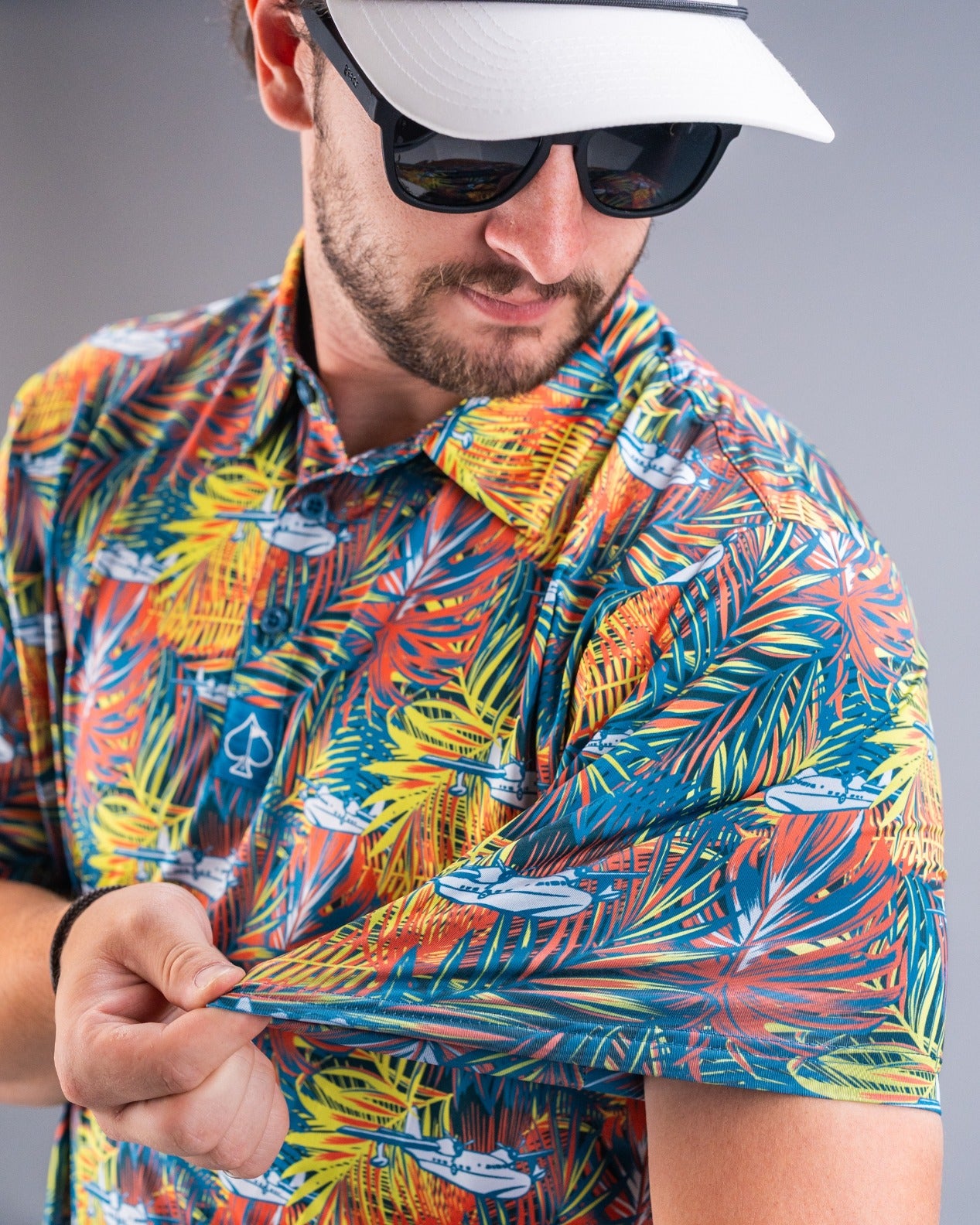 Colorful Margaritaville Bama Breeze shirt featuring a tropical palm leaf pattern, worn by a man adjusting the sleeve.