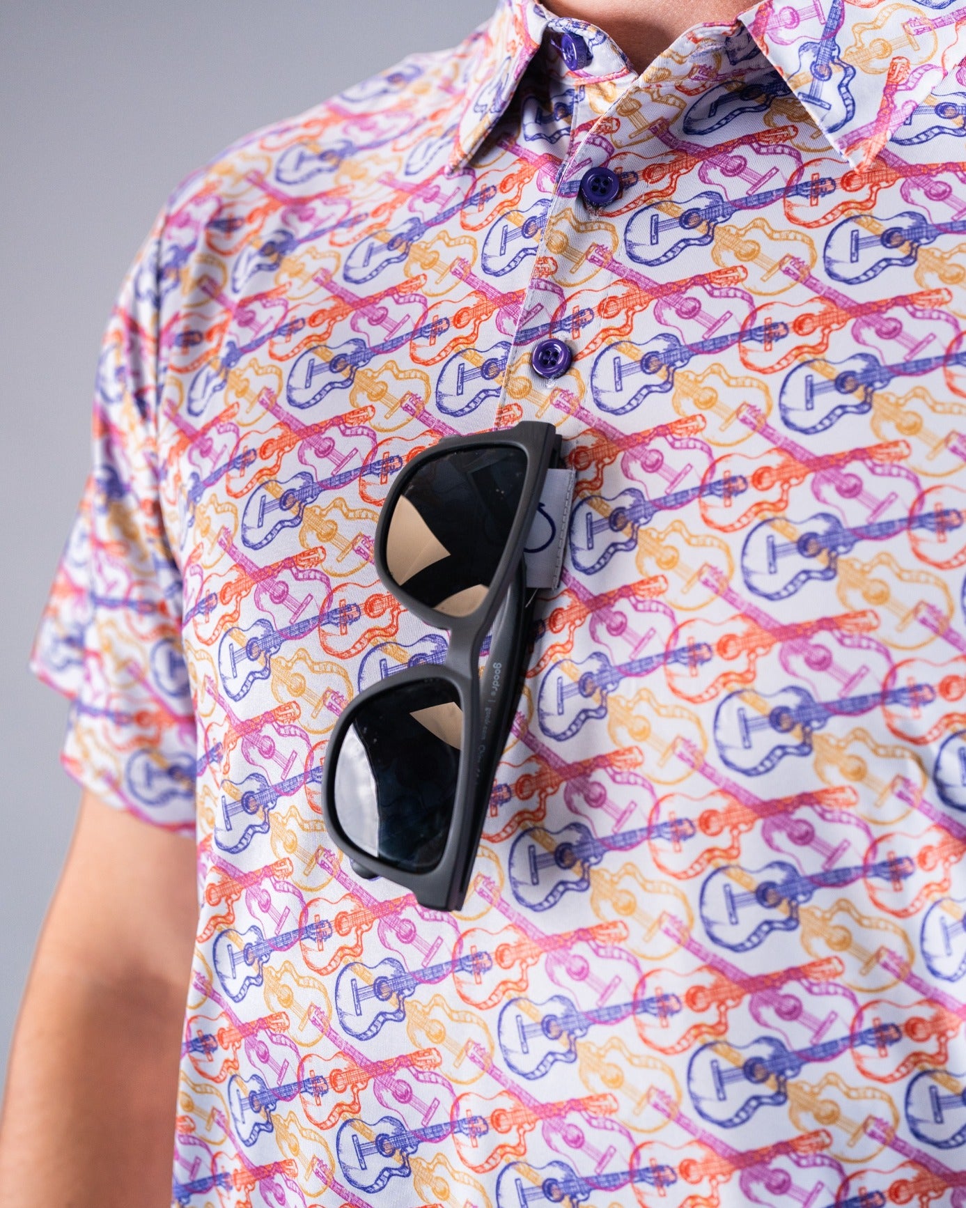 Colorful Margaritaville shirt featuring a guitar pattern, with sunglasses stylishly tucked into the collar.