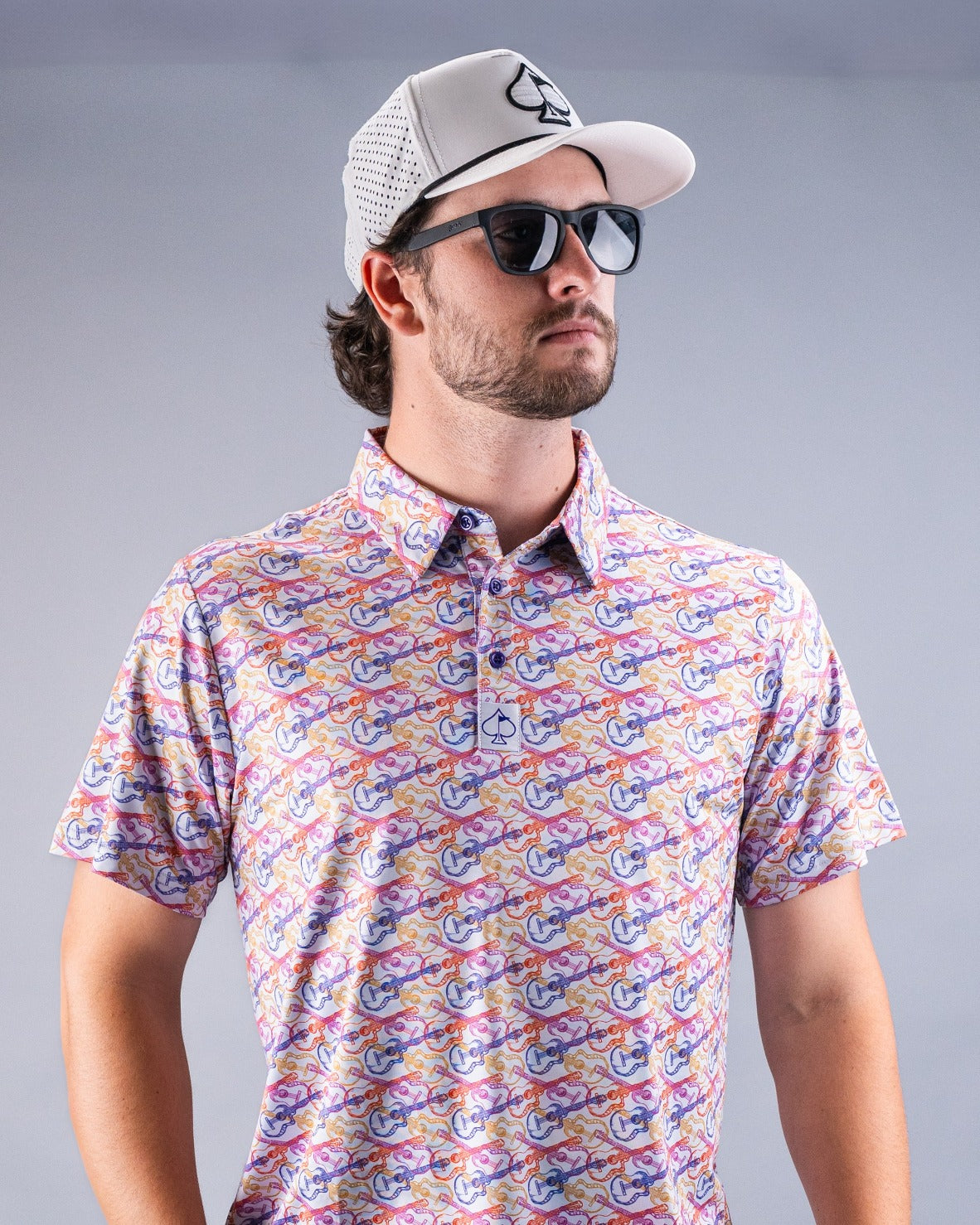 Model wearing a colorful Margaritaville polo shirt with a vibrant pattern, paired with sunglasses and a cap, exuding a relaxed vibe.