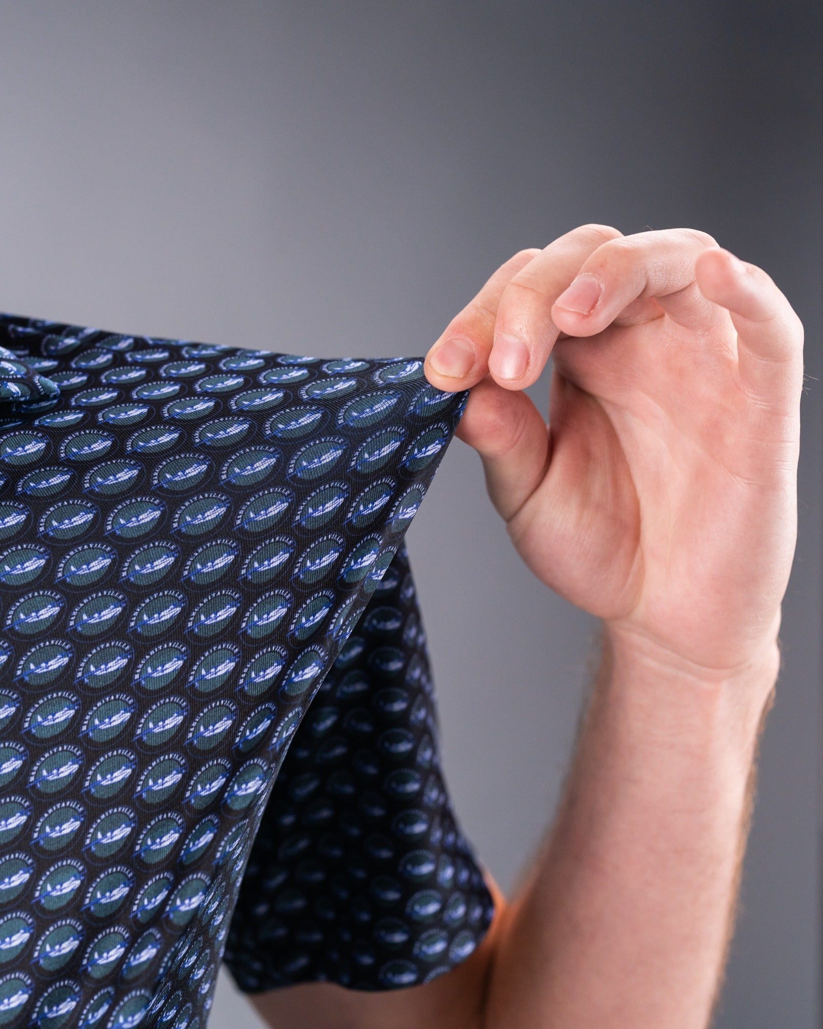Close-up of a person holding the sleeve of a Margaritaville Hemisphere Dancer shirt featuring a colorful pattern.