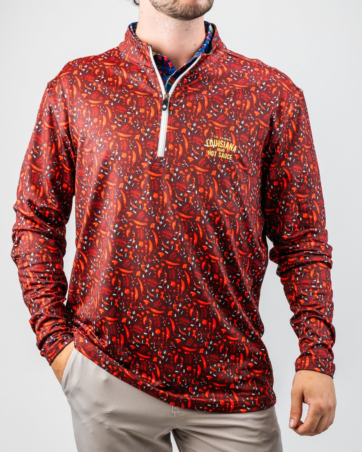 Bold red and black golf pullover with chili pepper pattern, "Louisiana Hot Sauce" logo, and quarter-zip front.