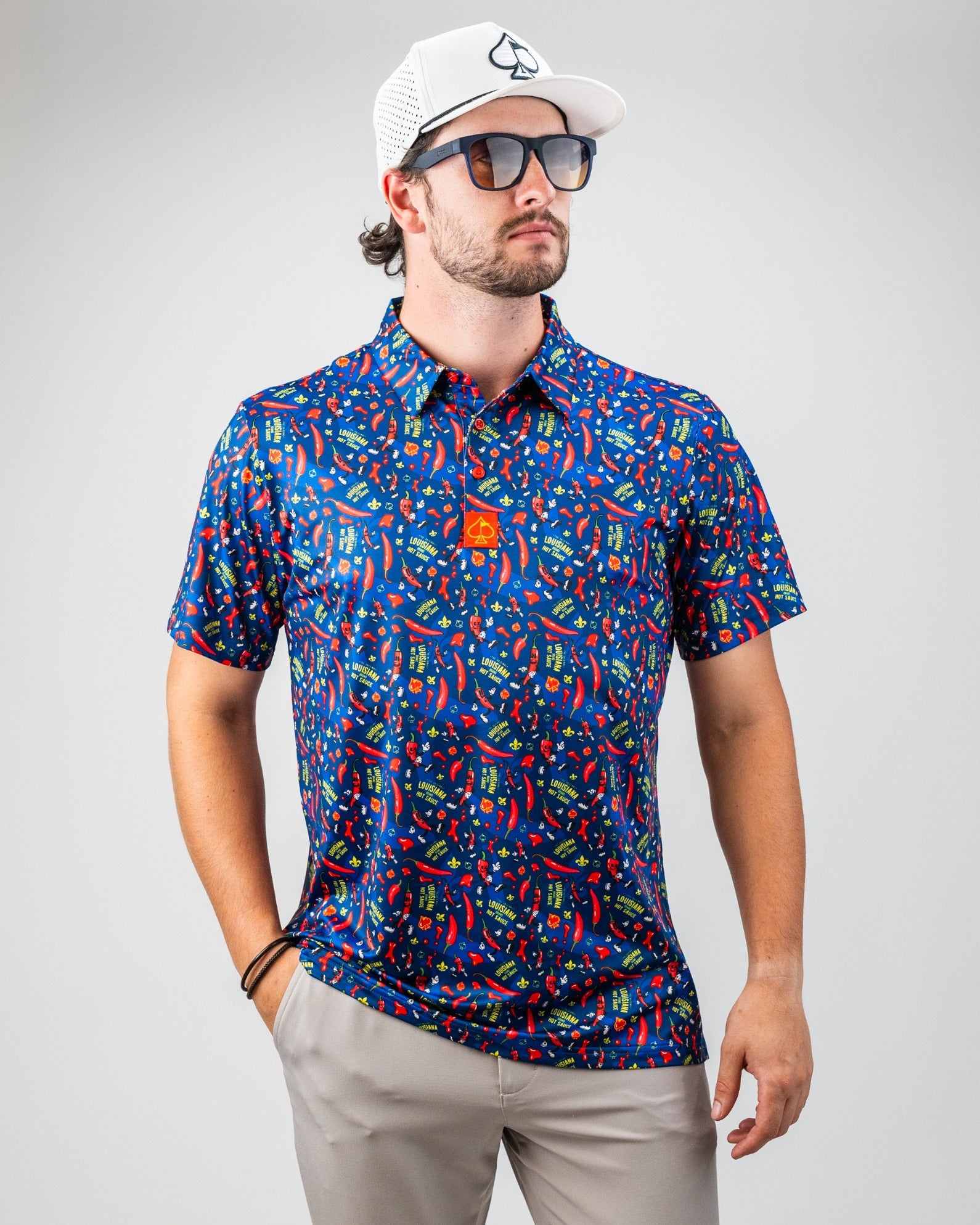 Bright blue golf shirt with colorful chili pepper, "Louisiana" text, and playful patterns for bold golf style.