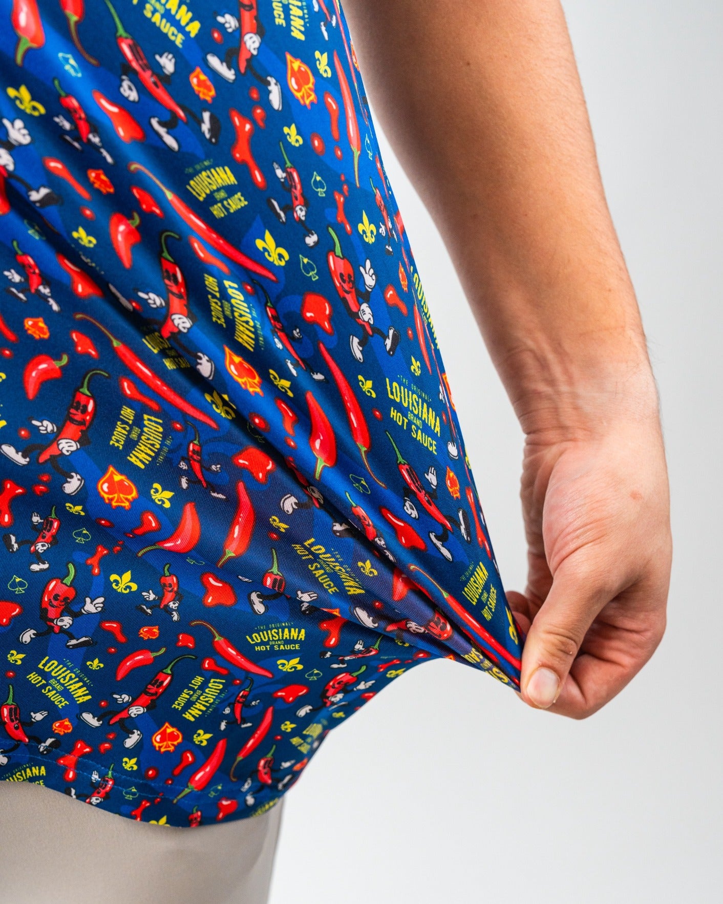 Bright blue golf shorts with red chili pepper, hot sauce, and Louisiana-themed graphics, perfect for bold golf style.