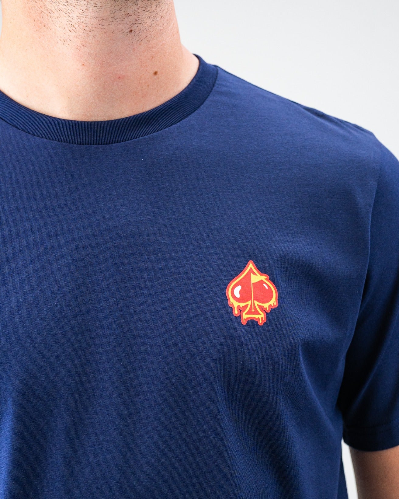 Close-up of navy golf t-shirt with a bold red and yellow spade logo on the chest, perfect for standout golf style.