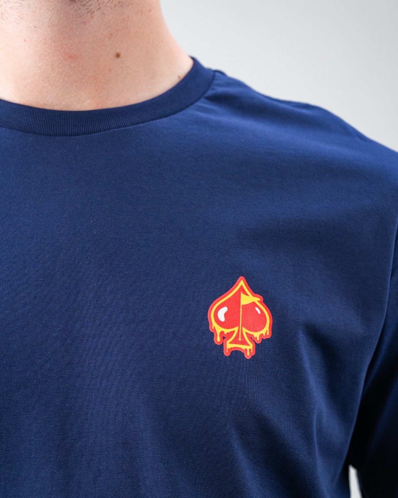 Navy blue golf t-shirt with a bold red and yellow spade logo on the chest, perfect for standing out on the course.