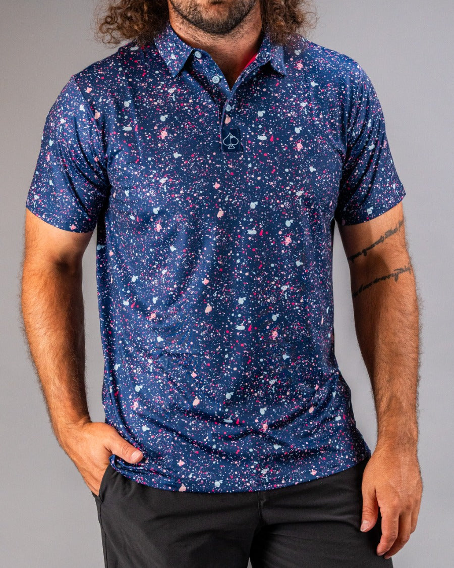 Men's blue splatter golf polo featuring a vibrant, abstract design with pink and white accents for a bold look on the course.
