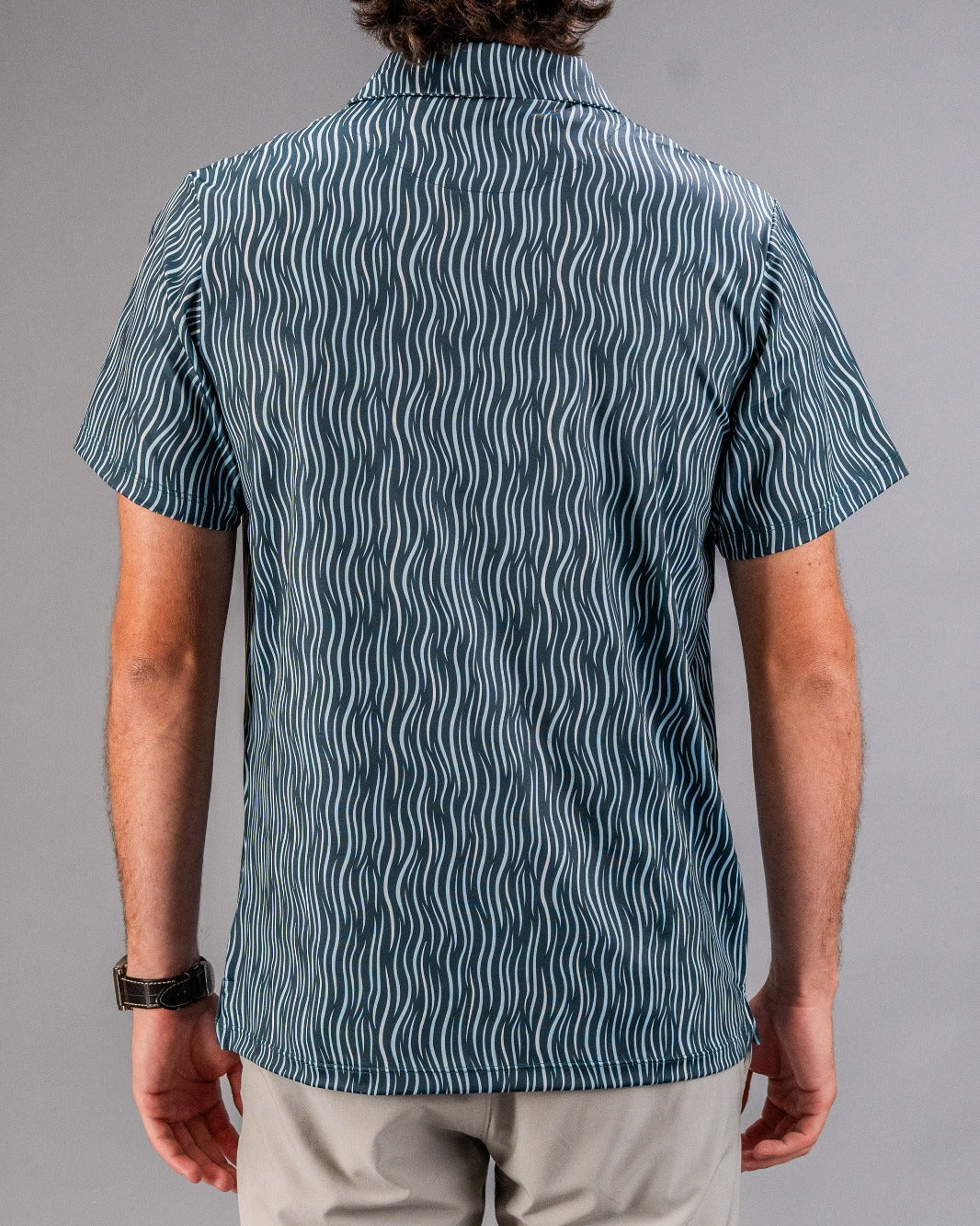 Bright blue golf shirt with white wavy line pattern, short sleeves, and collar, perfect for bold golf style.