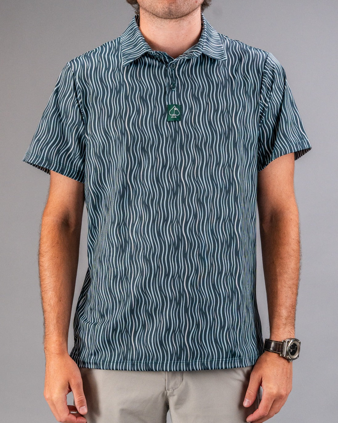 Men's short-sleeve golf shirt with a wavy pattern in teal and white, featuring a button-down collar and a logo tag.