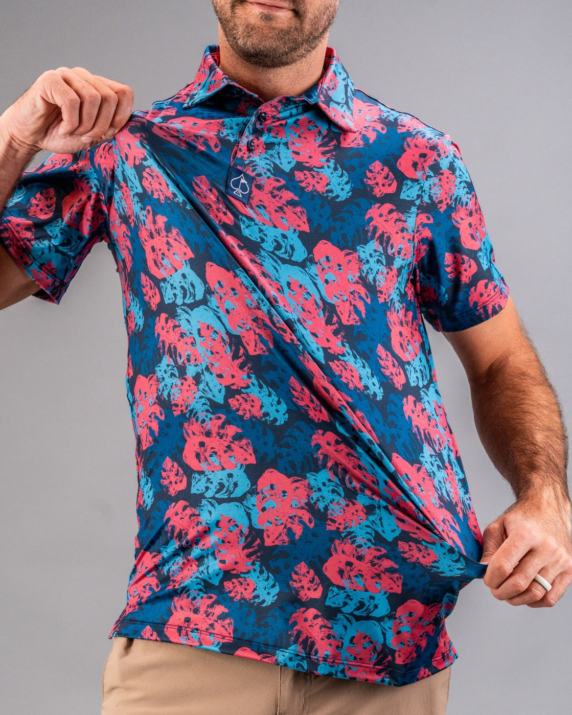 Bright blue and pink tropical leaf print golf shirt with short sleeves, collared neckline, and bold, eye-catching design.