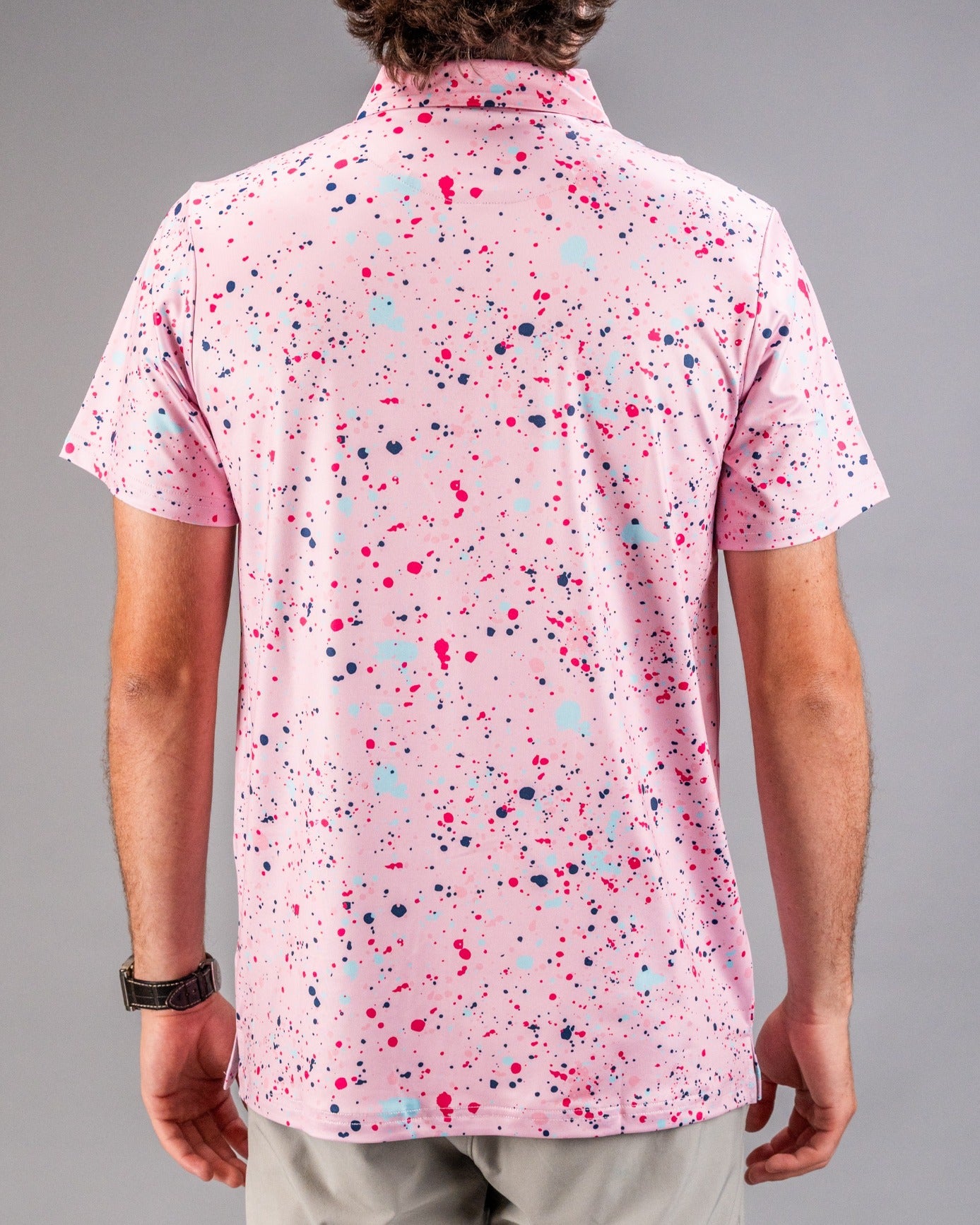 Men's pink golf shirt featuring a vibrant splatter pattern in blue and dark pink, perfect for a bold look on the course.