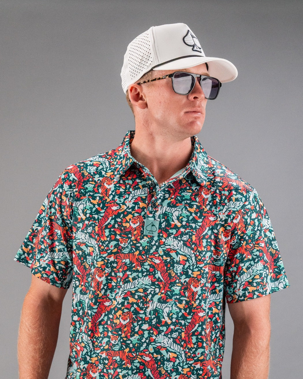 Bold Tiger Shatter Teal golf shirt featuring a vibrant floral and tiger print, paired with a stylish cap and sunglasses.