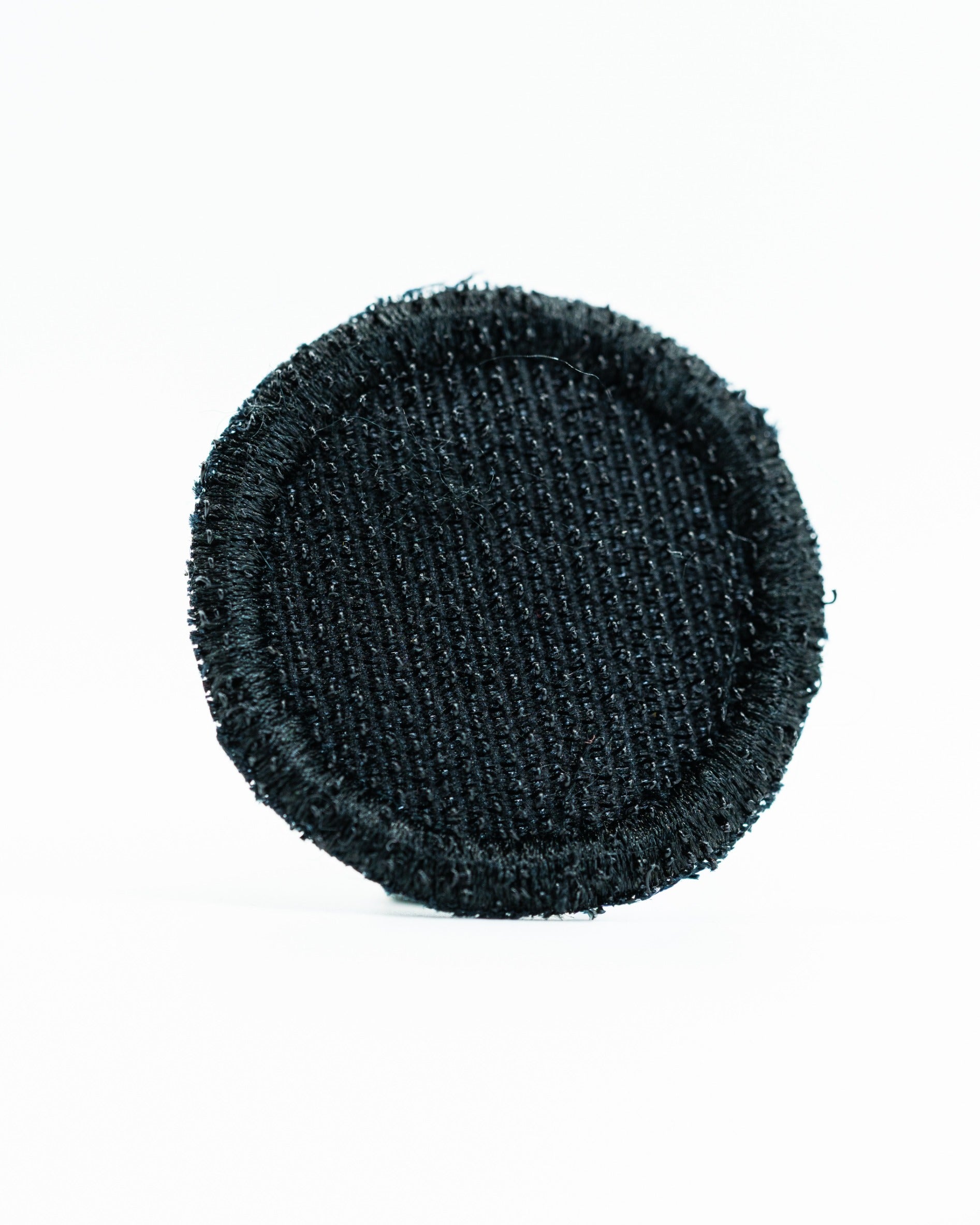 Black round headcover patch with a textured fabric surface, designed for golfers seeking a sleek accessory.
