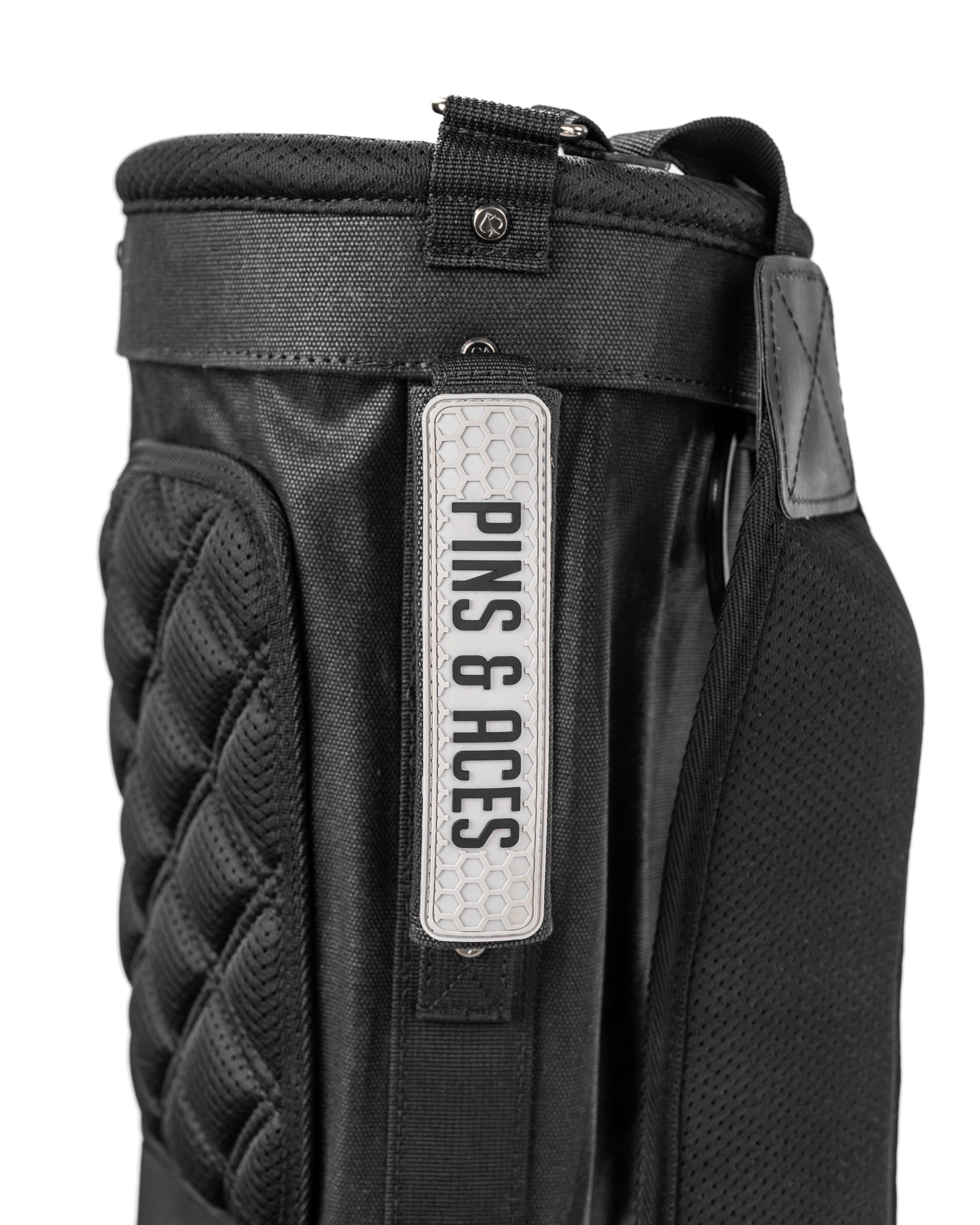 Sleek black Sunday golf bag featuring a textured design and a prominent Pins and Aces logo for stylish on-course performance.