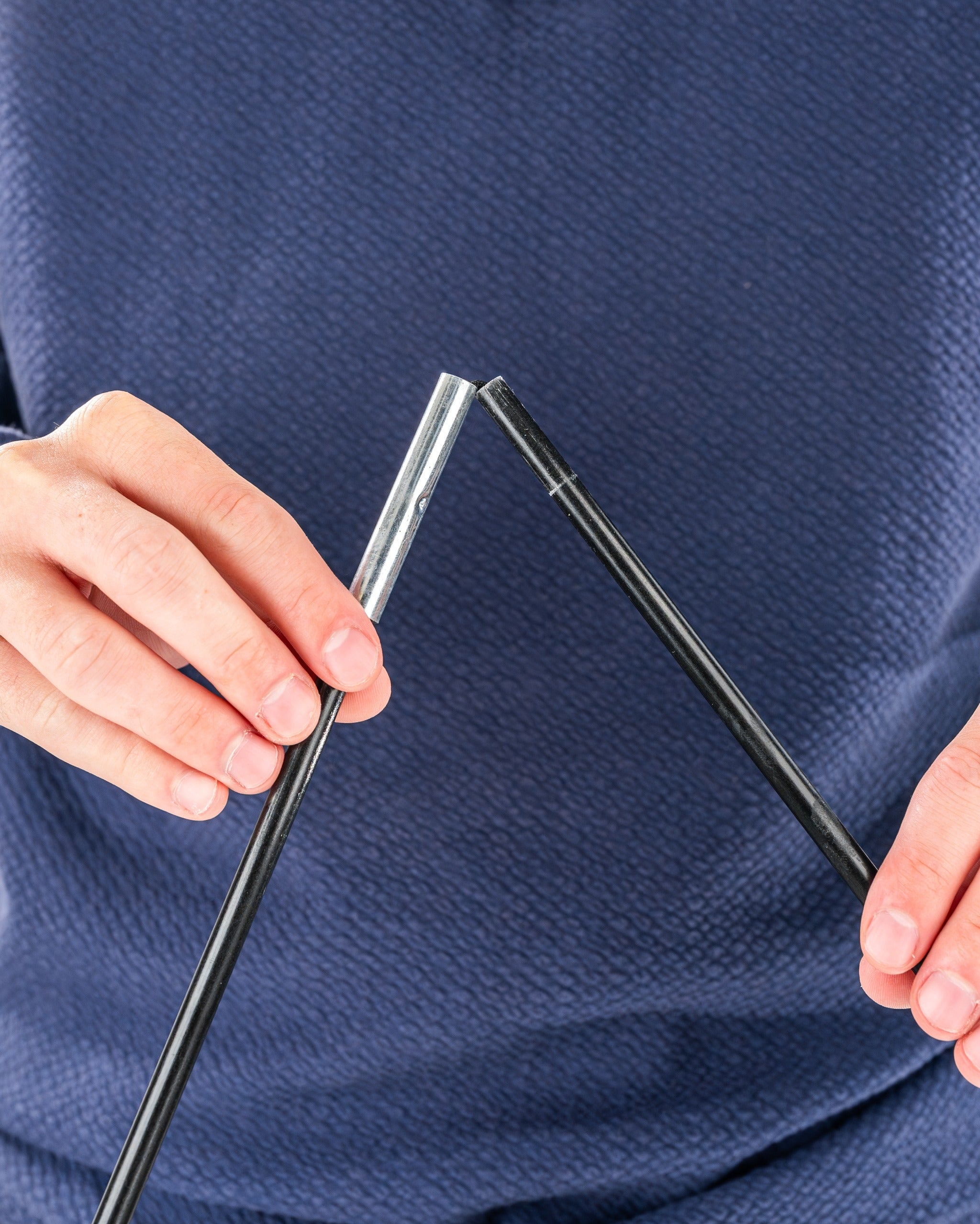 Person demonstrating the assembly of a Sunday golf bag with two connecting poles for easy setup on the course.
