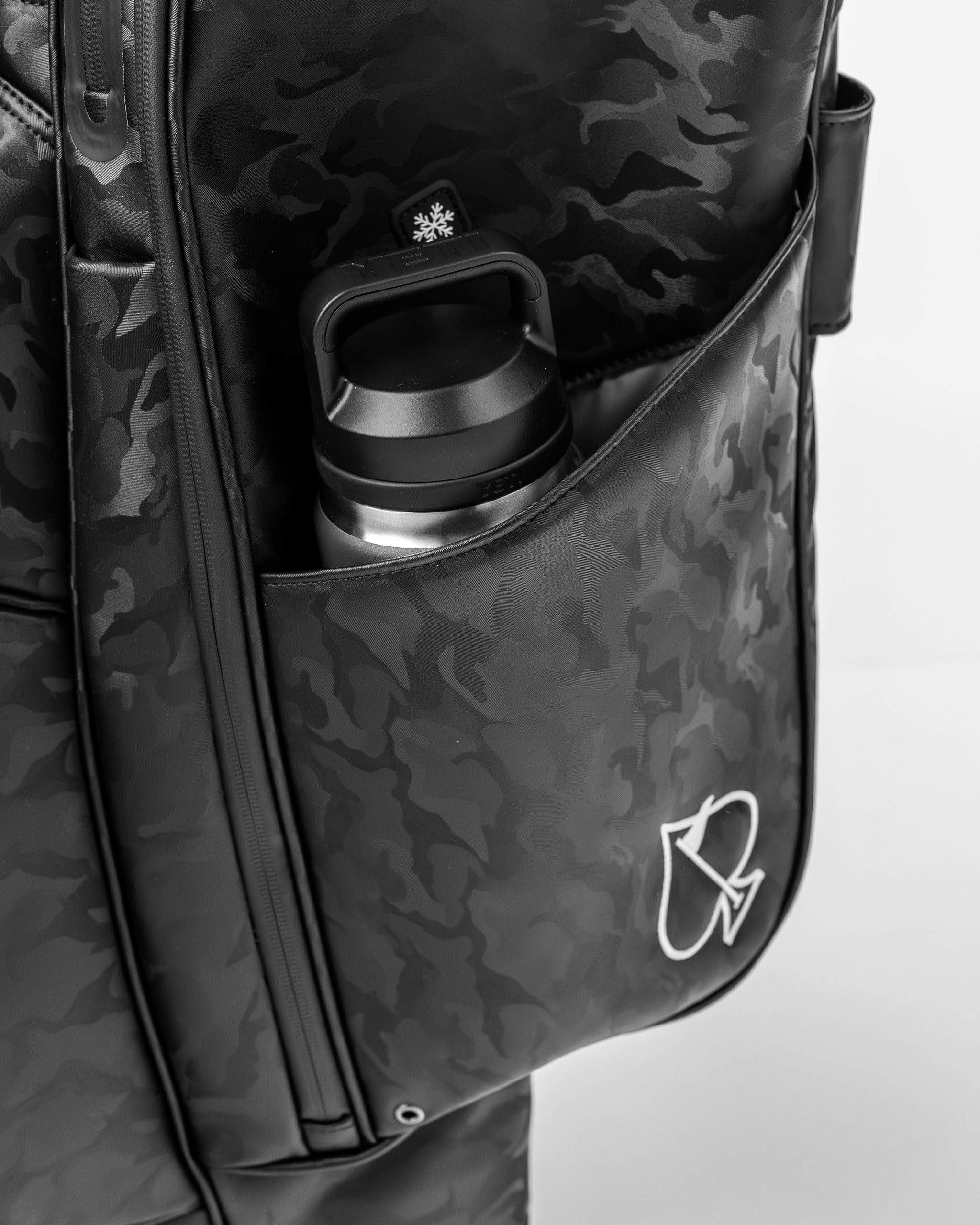 Black camo golf bag featuring a side pocket with a water bottle, showcasing a sleek and stylish design for golfers.