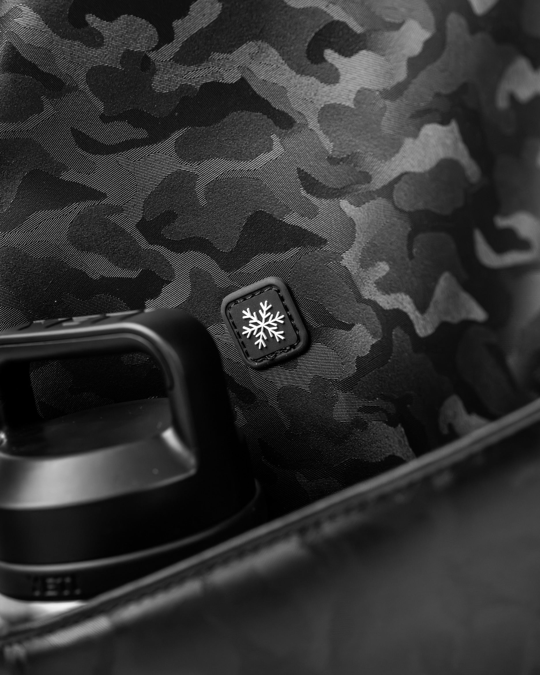 Black camo golf bag featuring a sleek design and a snowflake logo, ideal for stylish golfers on the course.