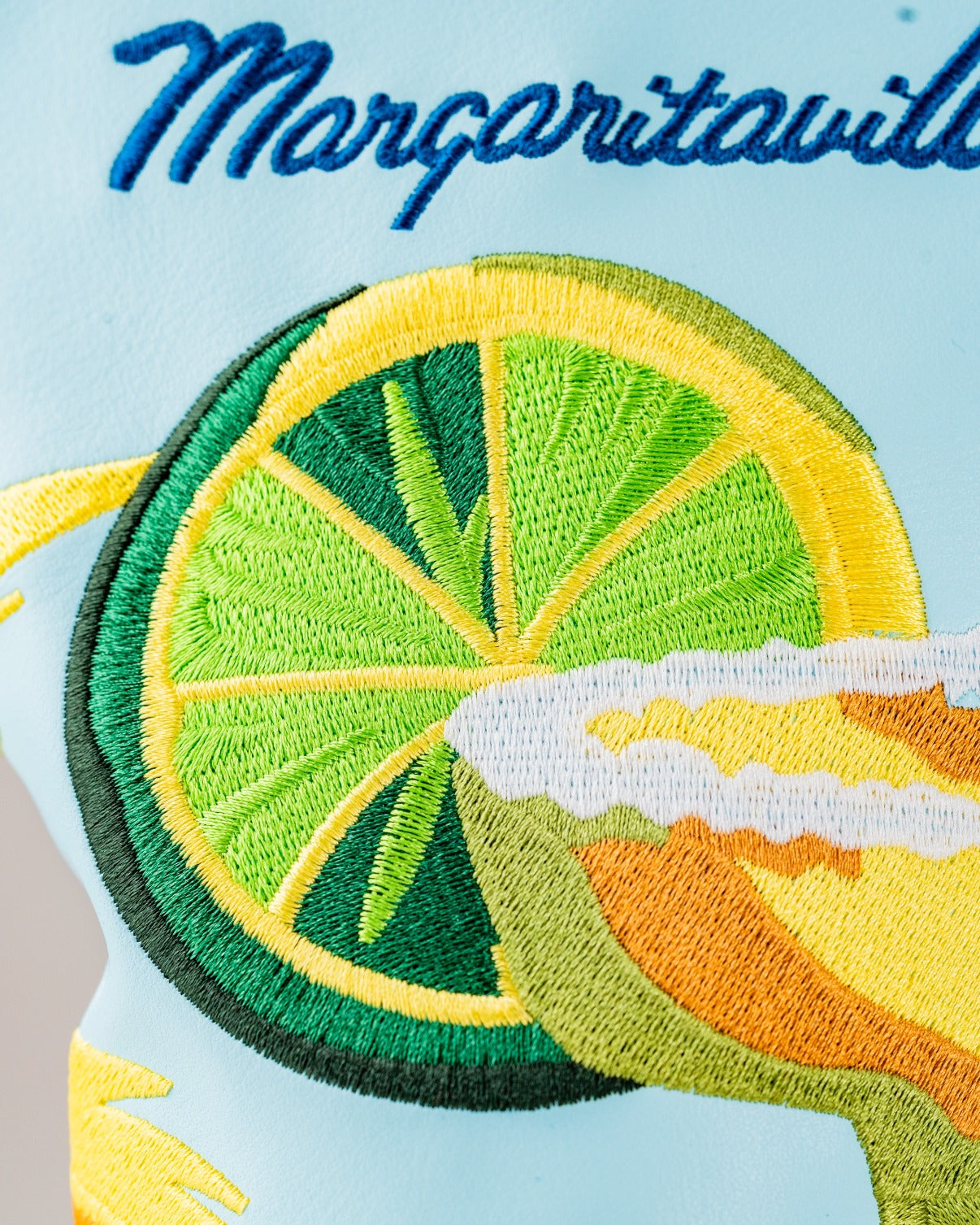 Embroidered design of a margarita glass and lime slice on a light blue golf headcover from Margaritaville.