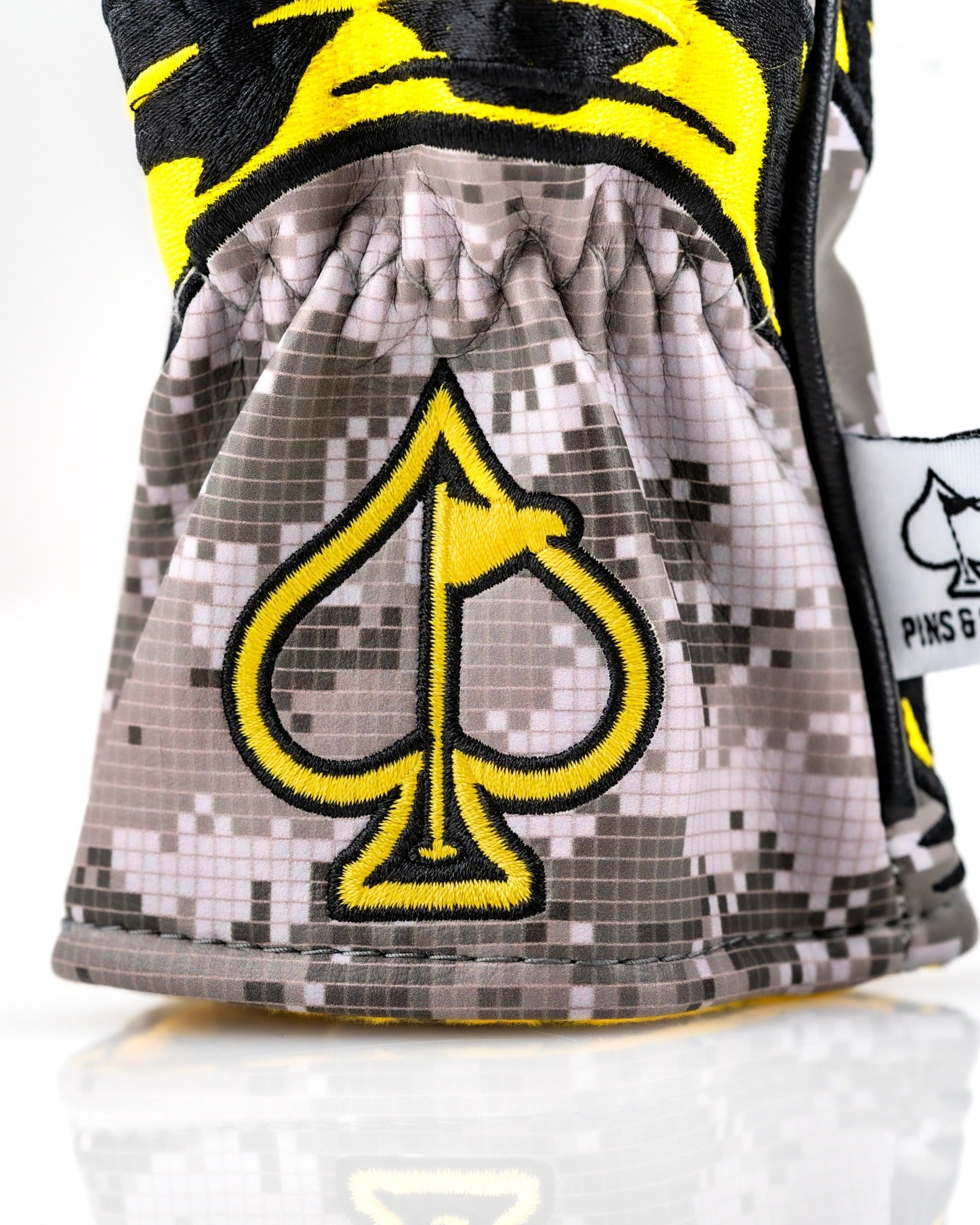 Hybrid golf headcover featuring a bold yellow and black design with a spade logo and camouflage pattern.