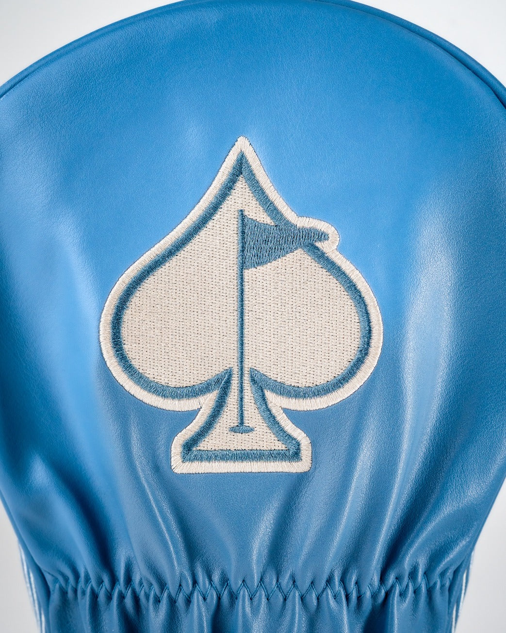 Blue driver cover featuring a spade emblem with a flag, designed for a bold western aesthetic in golf apparel.