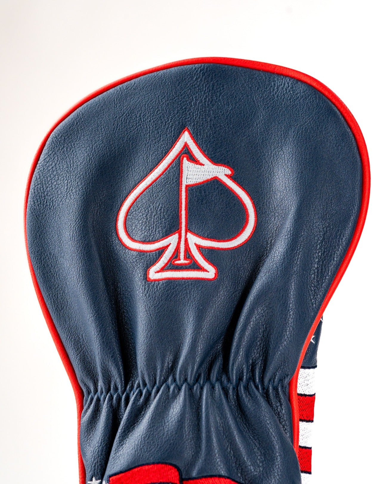 Bold navy driver cover featuring a red and white striped design with an embroidered spade logo and flag detail.