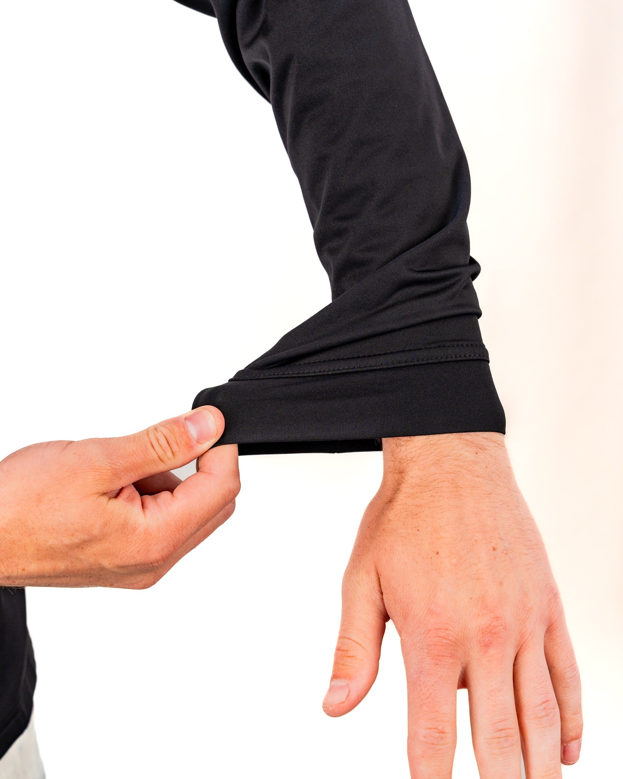 A person adjusting the sleeve of a black performance golf hoodie, showcasing its flexible fabric and design.