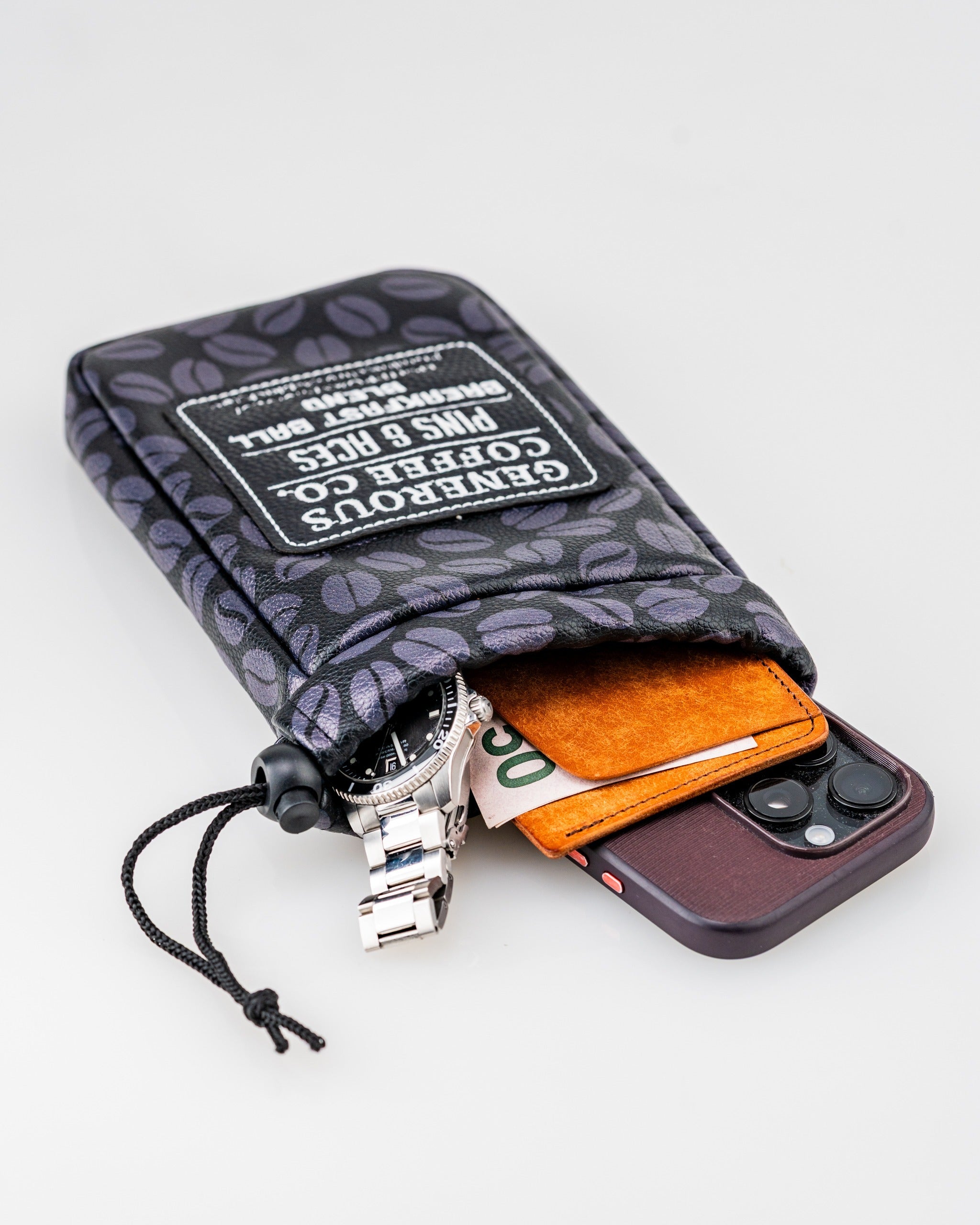 Generous Coffee valuables pouch featuring a coffee bean pattern, holding a phone, wallet, and watch, with a drawstring closure.