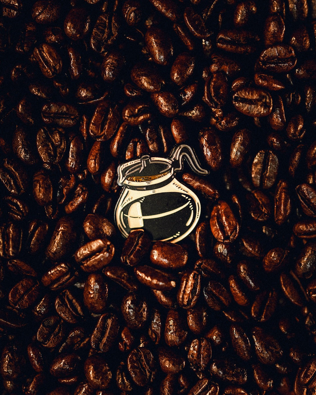 Coffee pot ball marker surrounded by roasted coffee beans, perfect for golfers who love coffee-themed accessories.