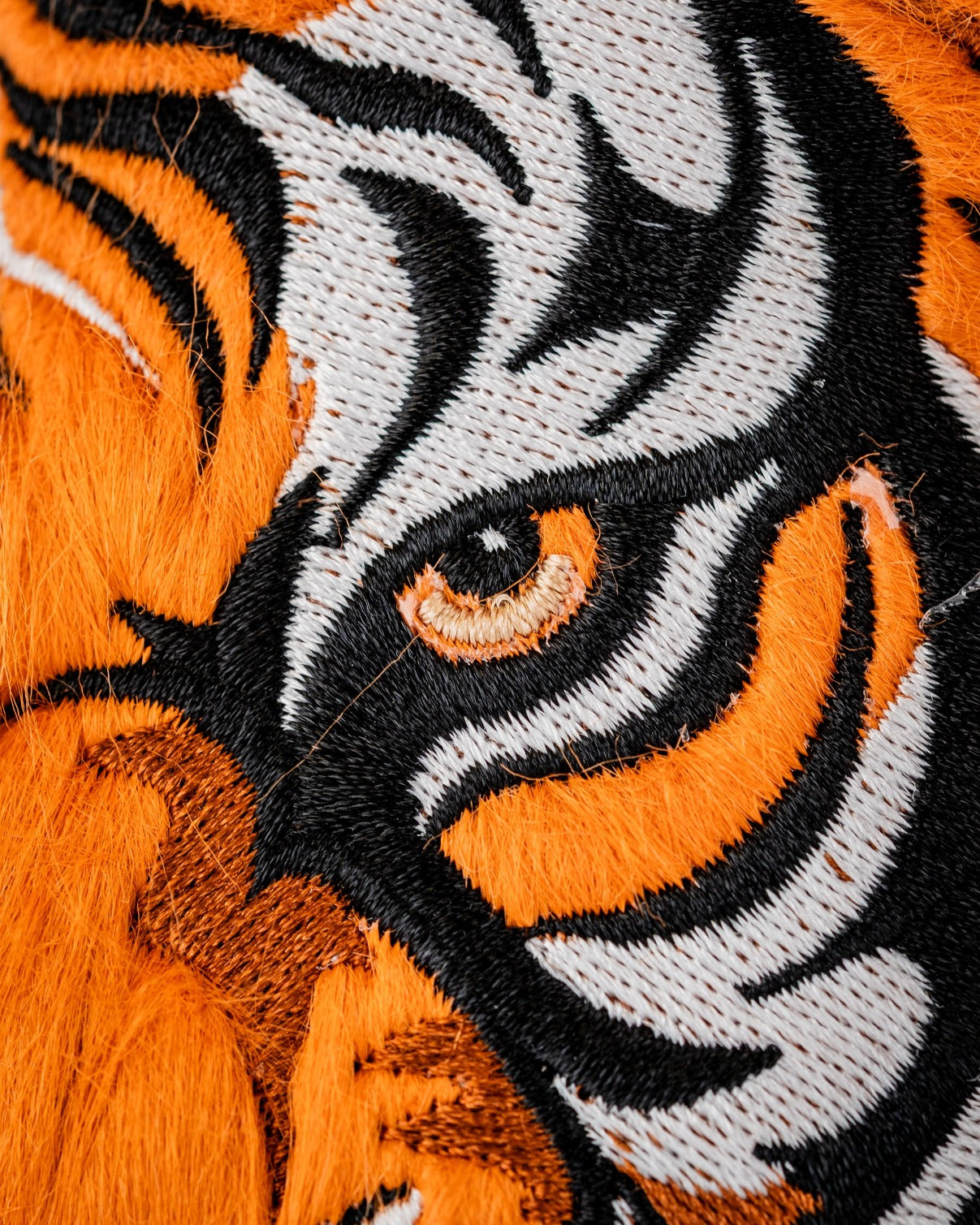 Close-up of a vibrant orange and black tiger driver cover featuring detailed embroidery of a tiger's eye and stripes.