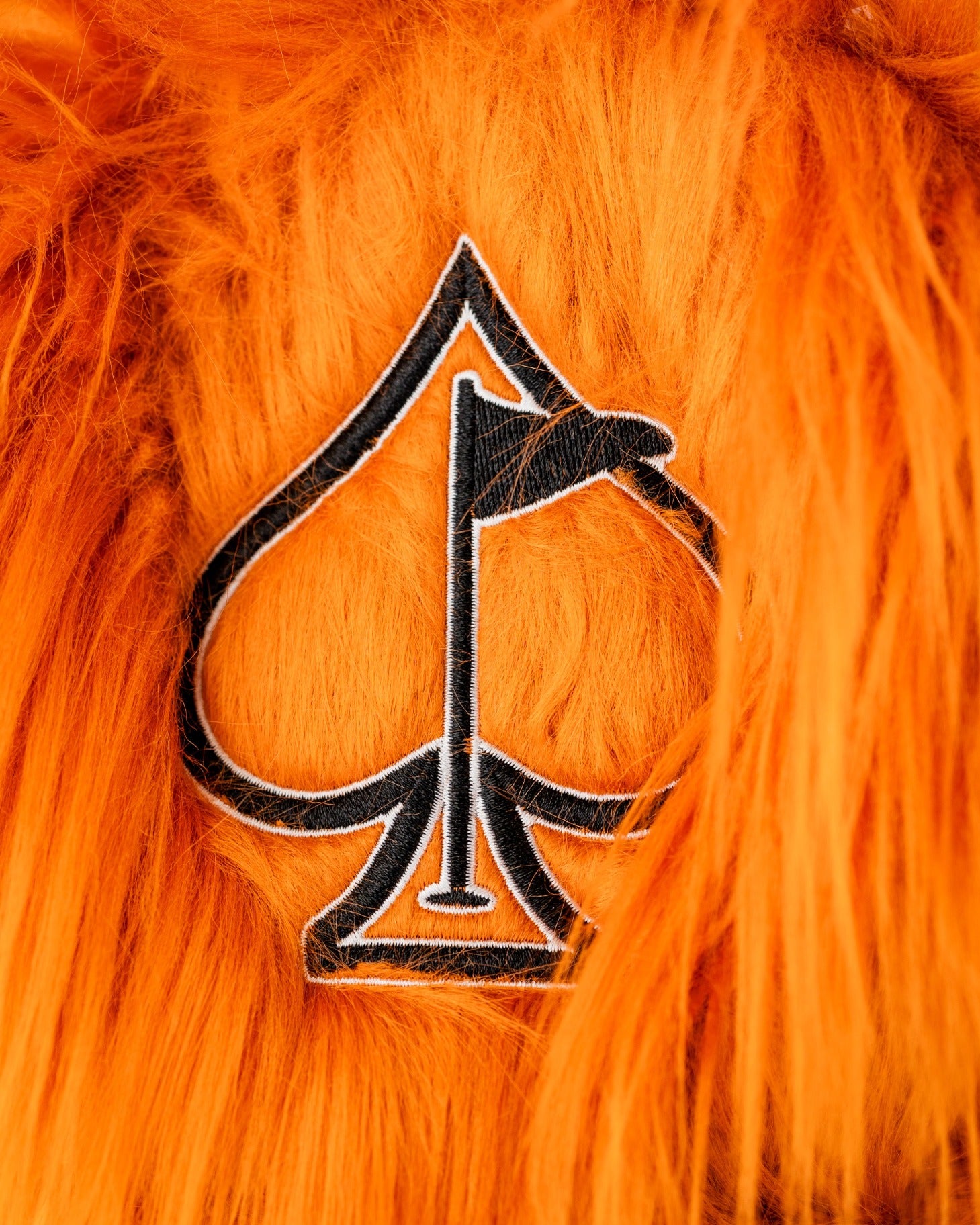 Bold orange driver cover featuring a black spade logo with a golf flag, designed for golfers who want to stand out.