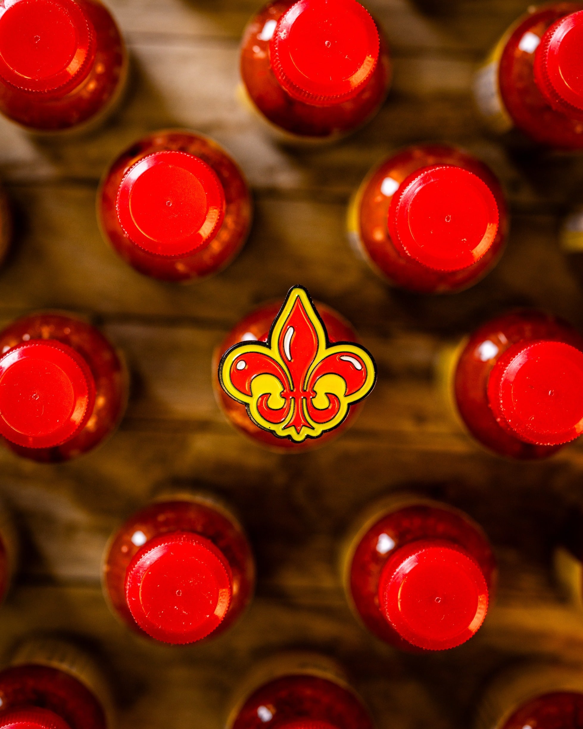 Fleur-de-lis ball marker centered among red bottle caps, showcasing a bold design perfect for golfers.