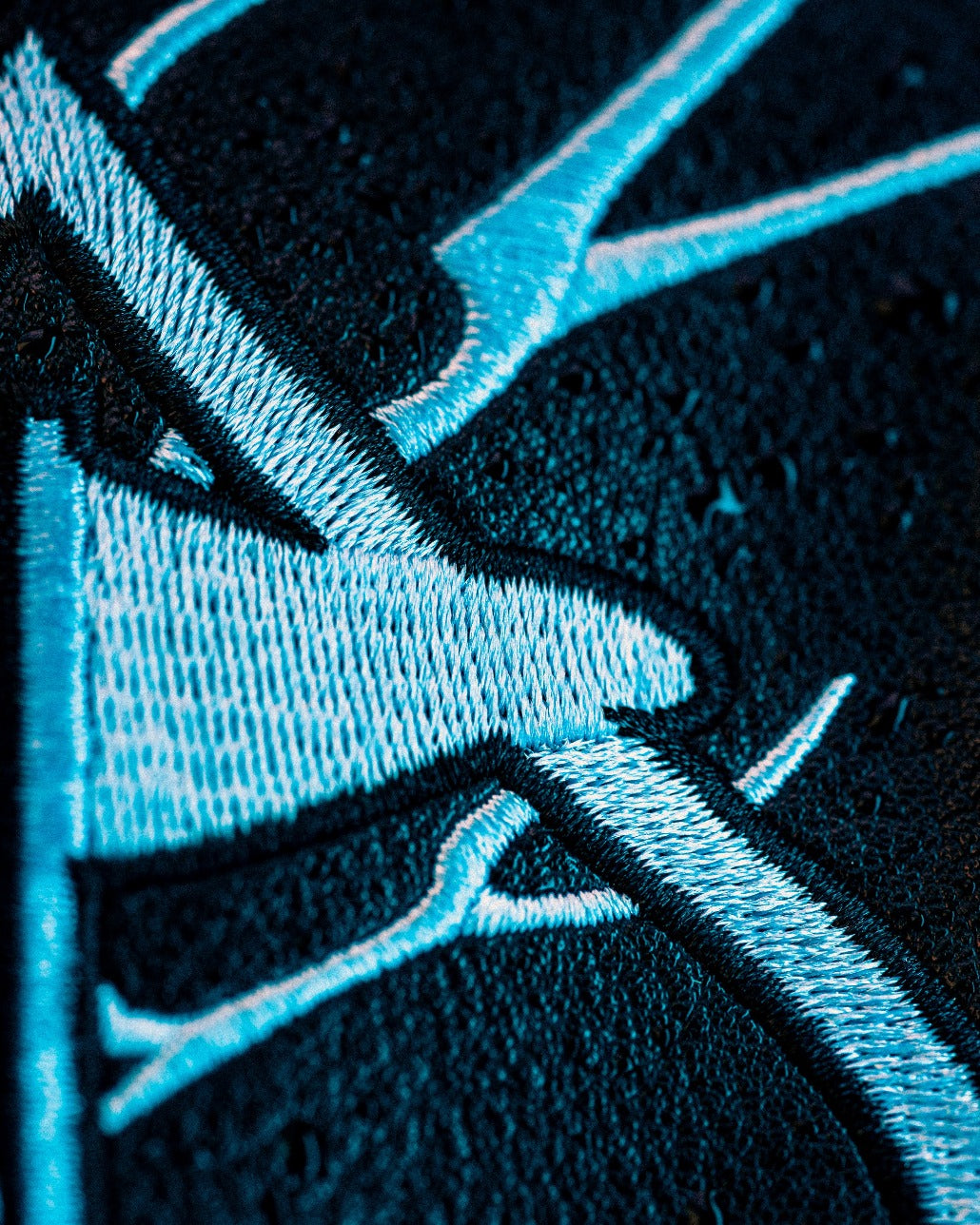 Close-up of intricate blue embroidery on a textured black fabric, showcasing the design from the Black Friday 2025 Mystery Box.