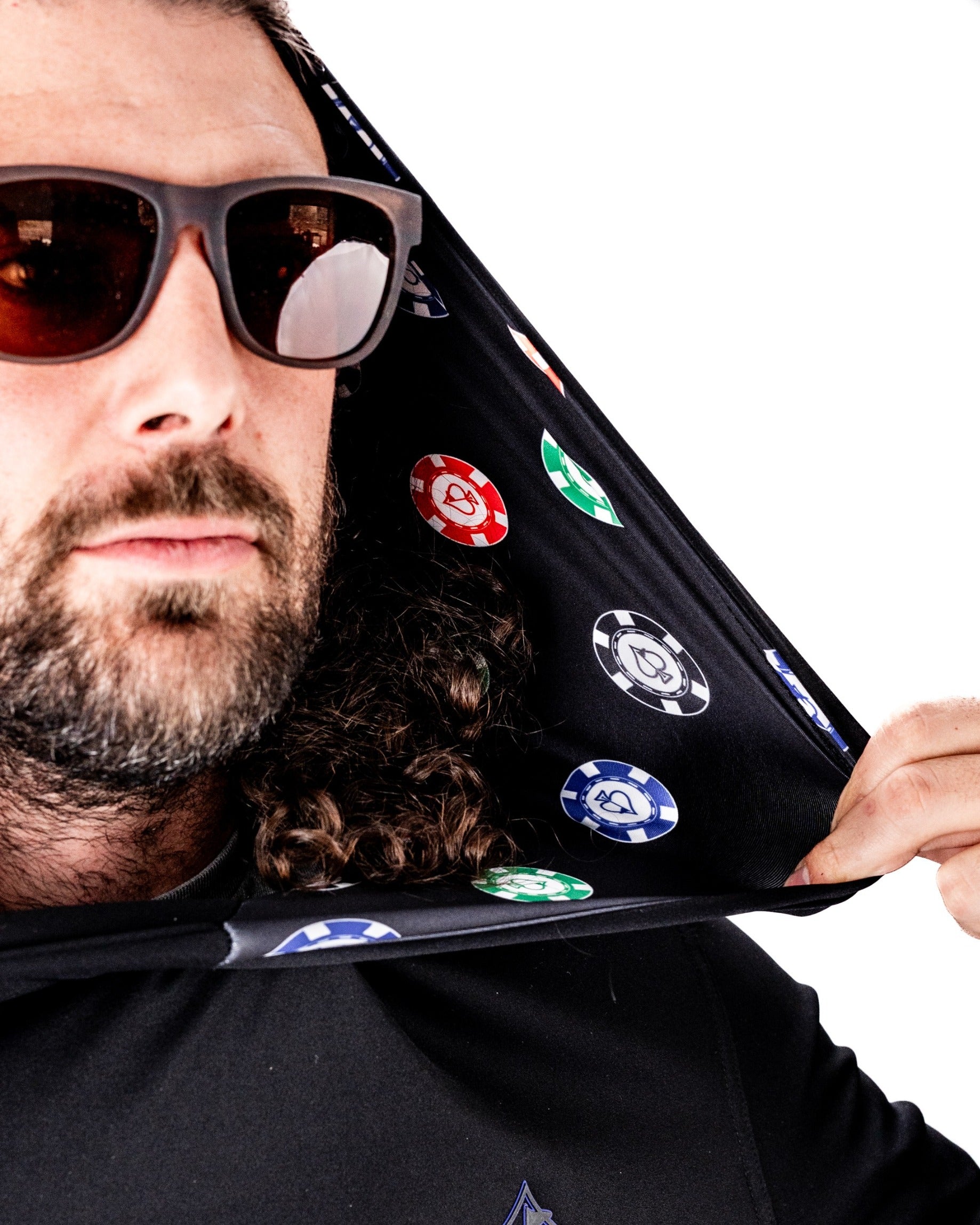 Man wearing a black performance golf hoodie featuring a poker chip design inside the hood, showcasing a stylish look.