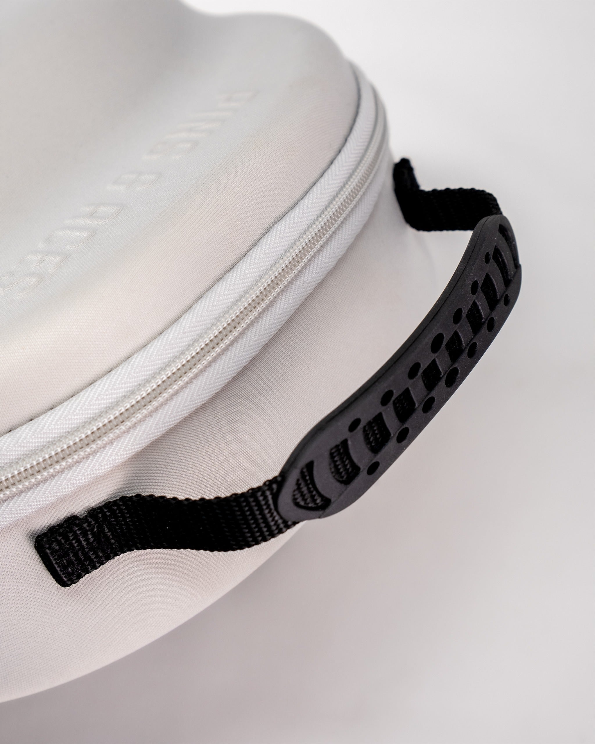 Close-up of the Hat Caddie, featuring a sleek white case with a textured black handle for easy transport.