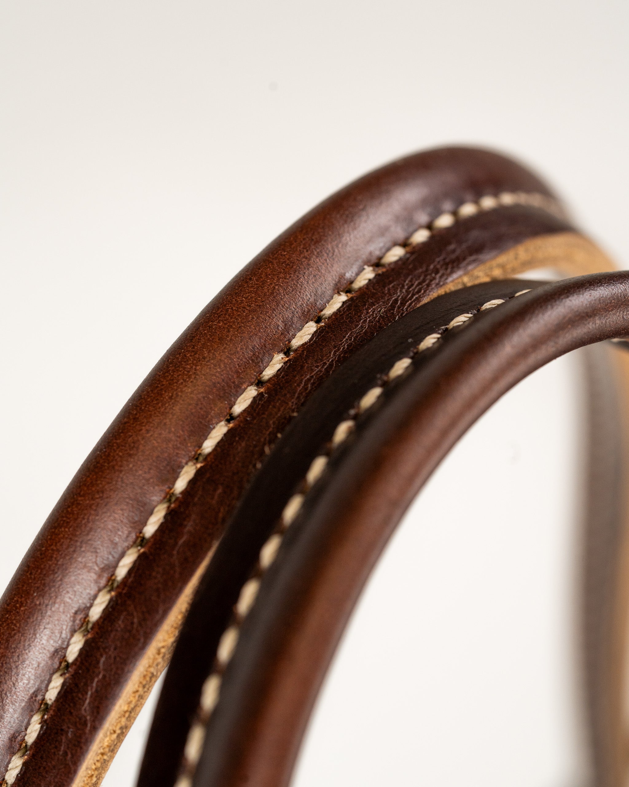 Close-up of two leather straps in different shades of brown, showcasing detailed stitching and texture.