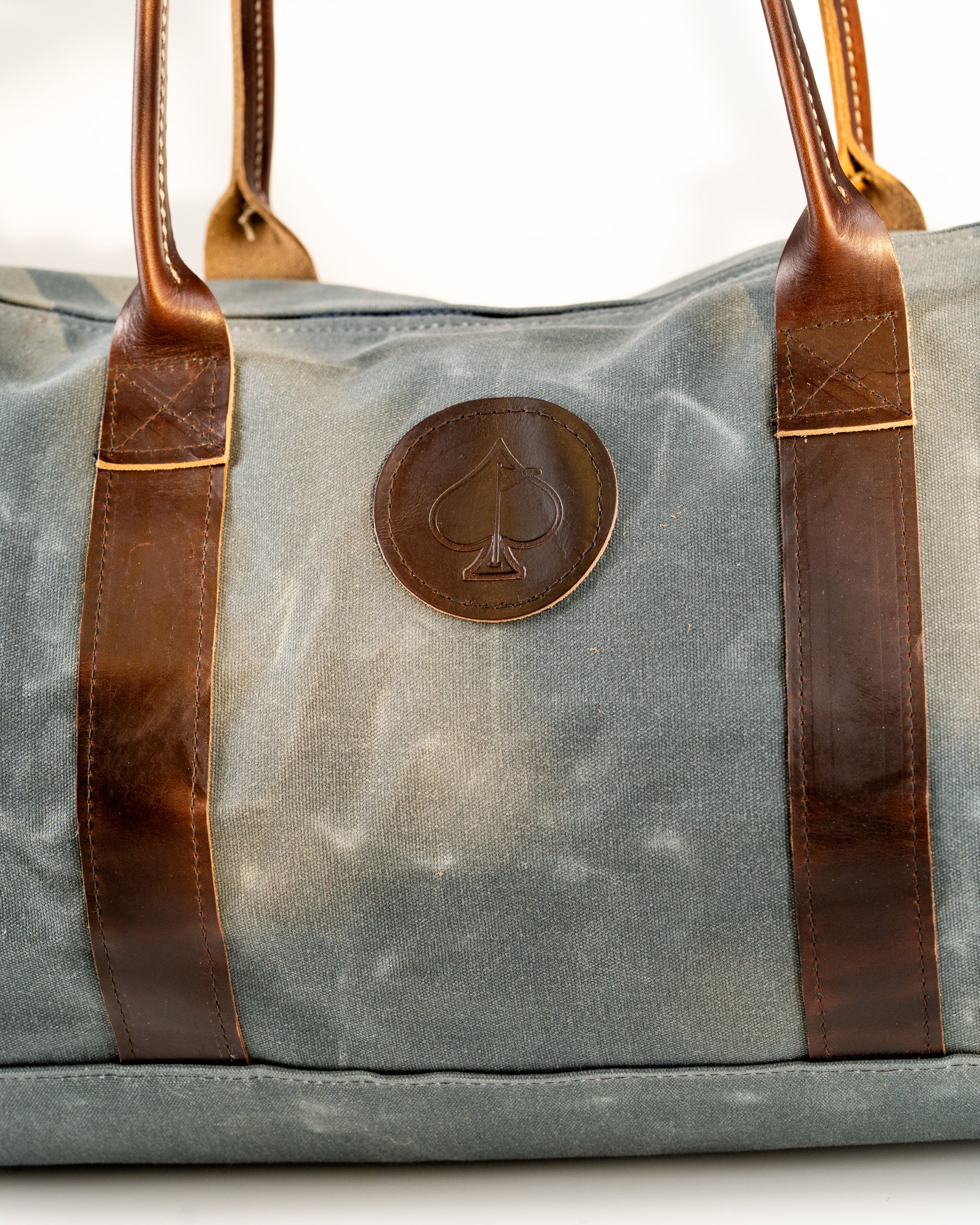 Stylish duffel bag featuring a durable canvas body and leather straps, perfect for golf gear or travel essentials.