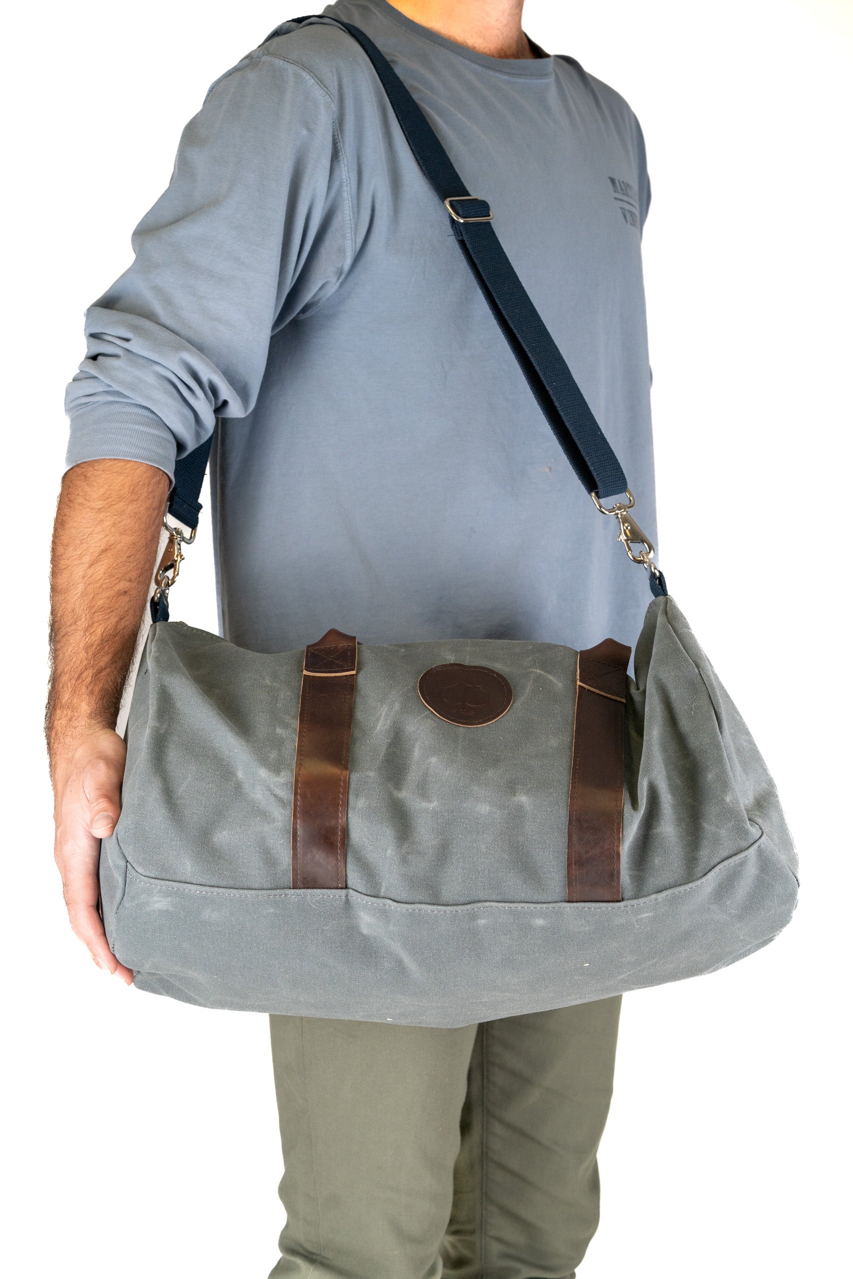 Stylish duffel bag with leather accents, perfect for travel or gym, held by a person wearing a casual outfit.