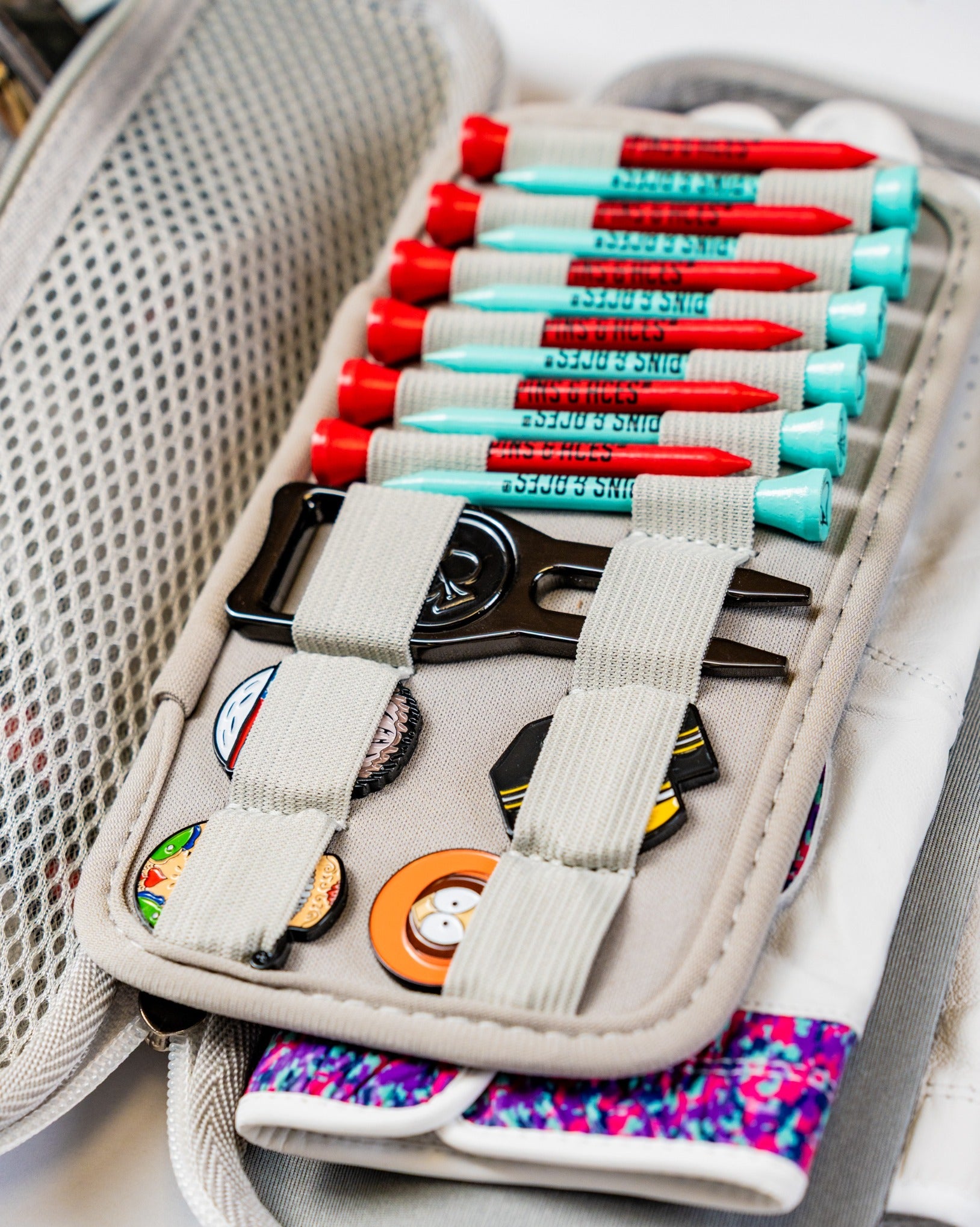 Gray glove and accessory caddie featuring organized golf tees, clips, and colorful pins for easy access on the course.