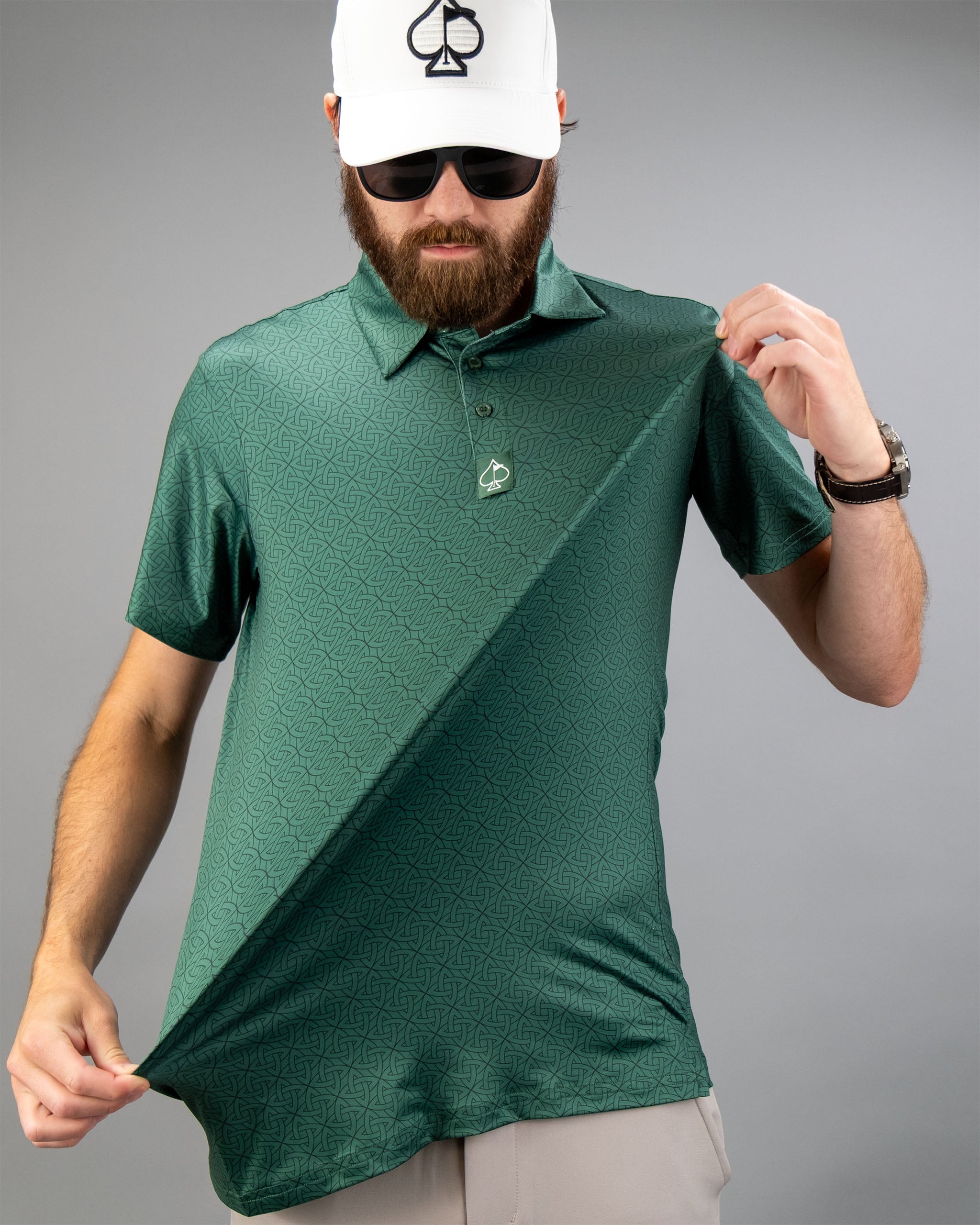 Model showcasing the Emerald Links polo shirt, featuring a textured green pattern and a logo, against a gray background.