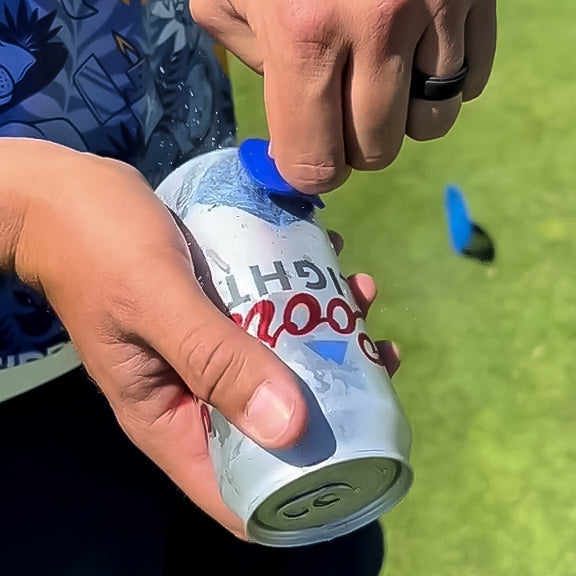 Close-up of a golfer opening a soda can, showcasing bold accessories and vibrant, eye-catching details for standout style ...