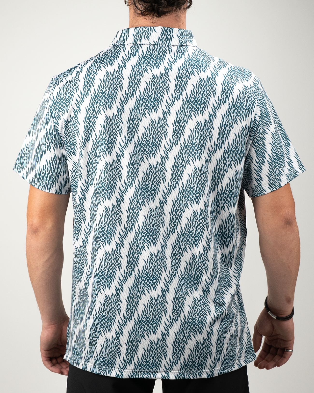 Men's short-sleeve golf shirt featuring a bold, abstract wave pattern in teal and white, designed for a standout look on the course.