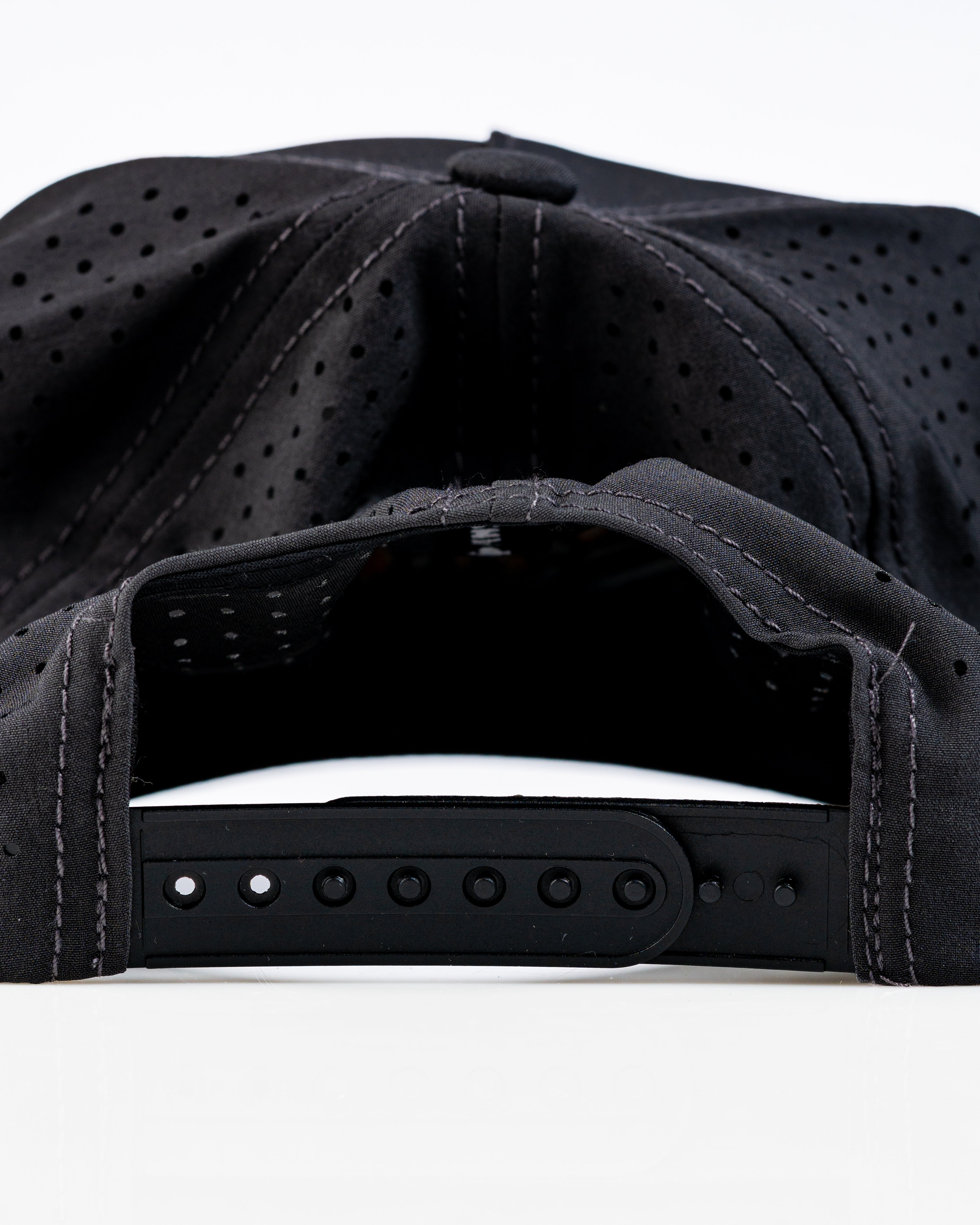 Perforated black rope hat with adjustable strap, featuring a sleek design for stylish golfers.