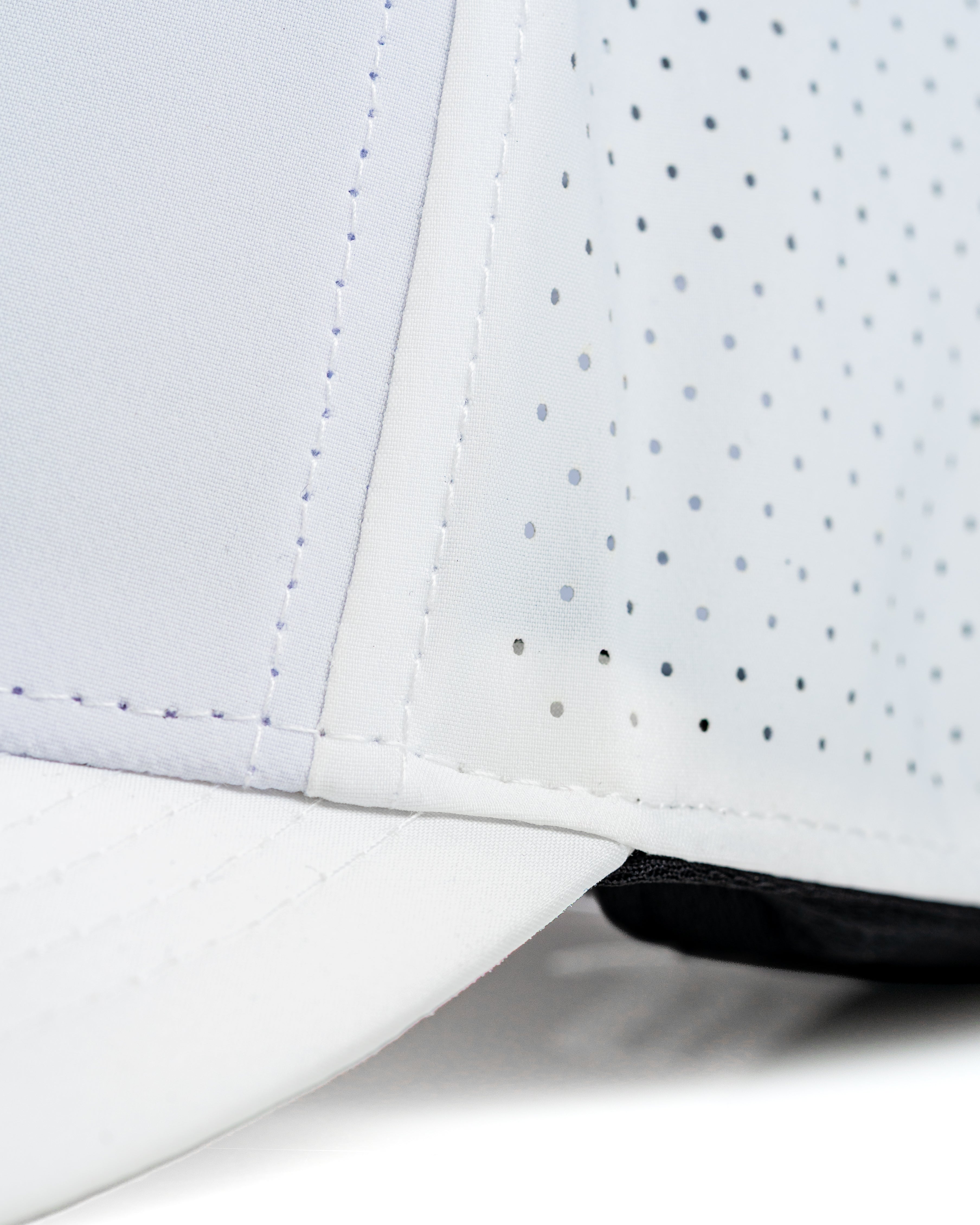 Close-up of the Tradesman Hat in white with perforated detailing, designed for comfort and breathability on the golf course.