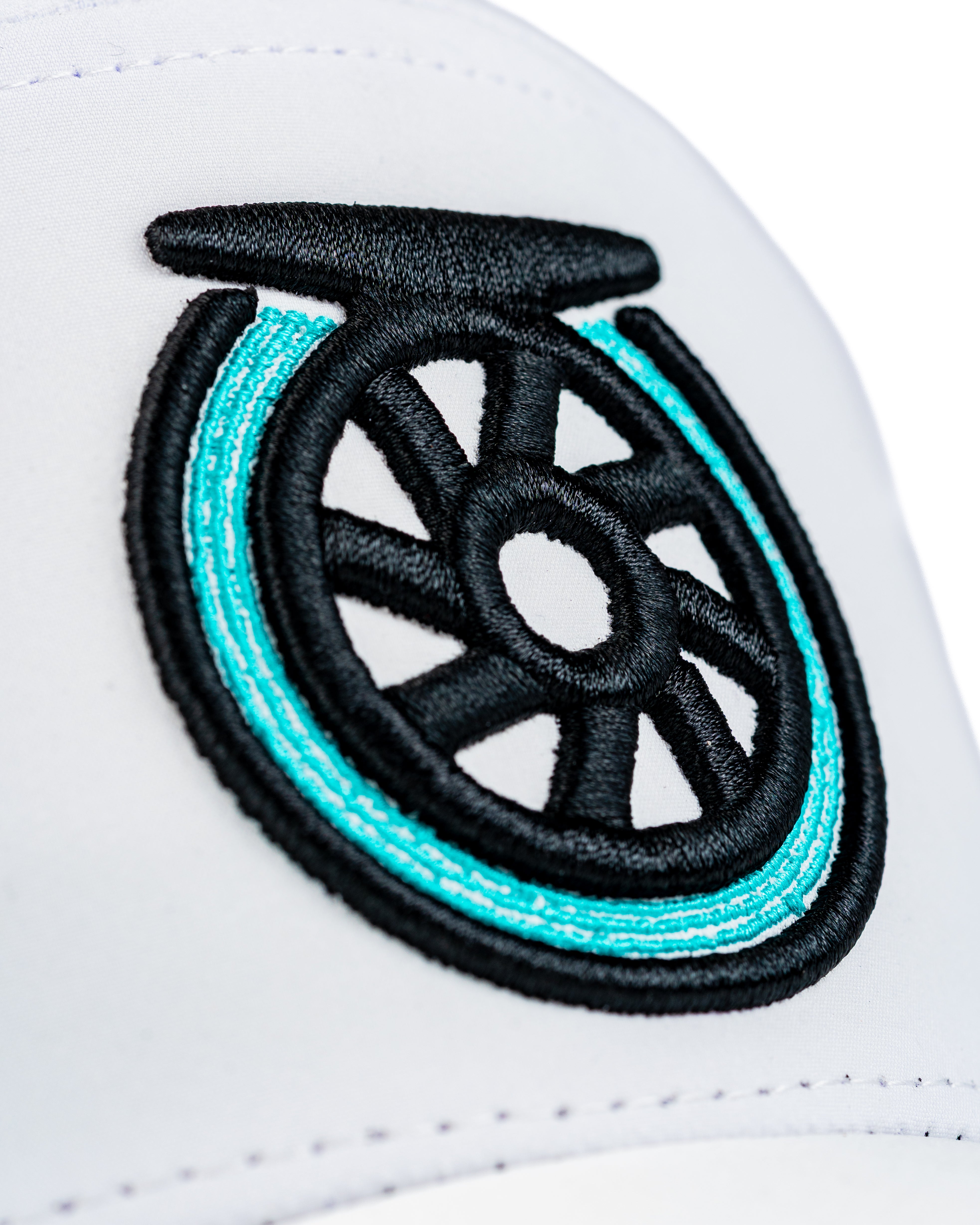 Close-up of the Tradesman Hat featuring a bold embroidered reel logo in black and turquoise on a white background.